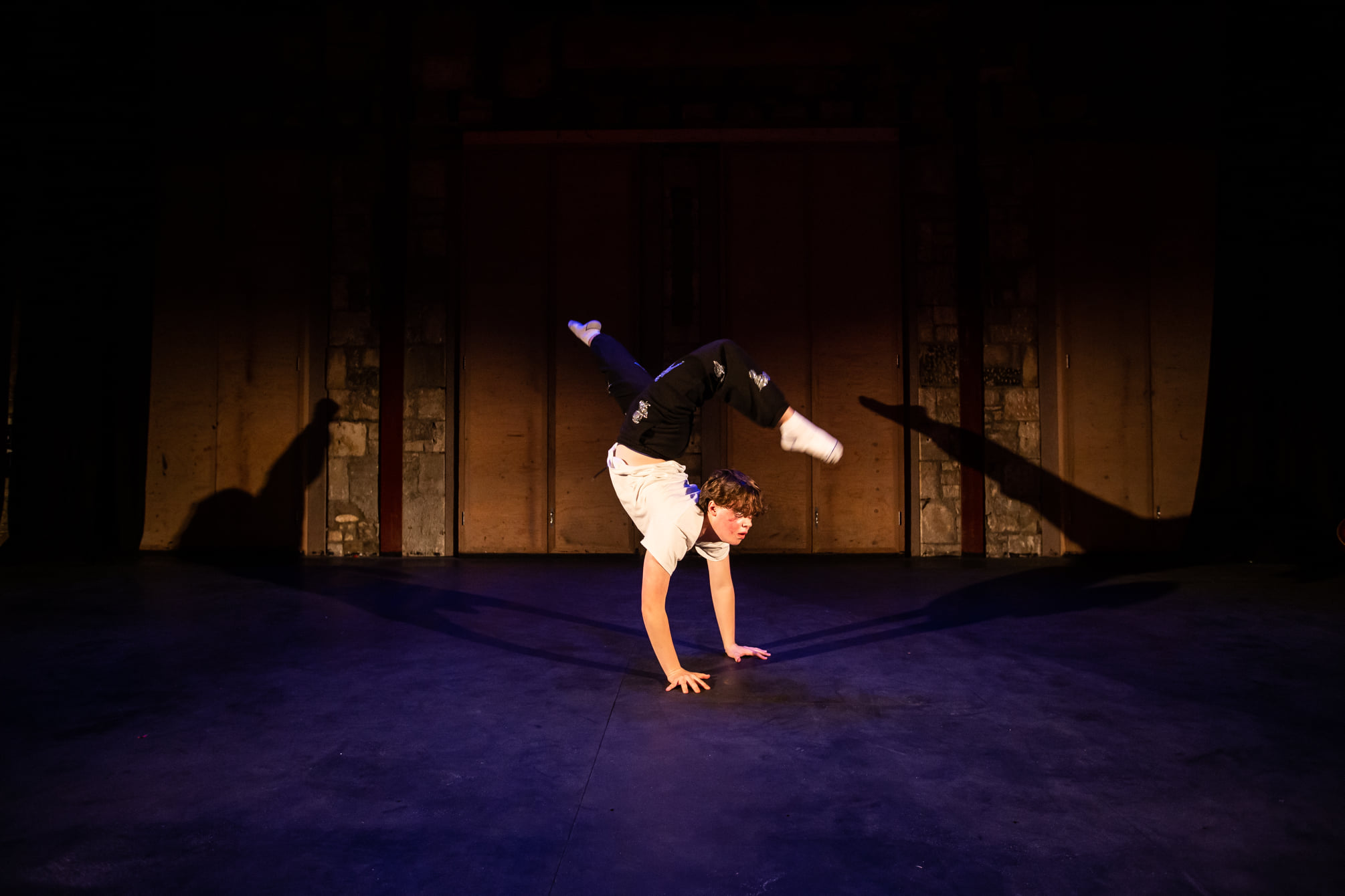 A young man performs a handstand split mid-way through a dance routine.