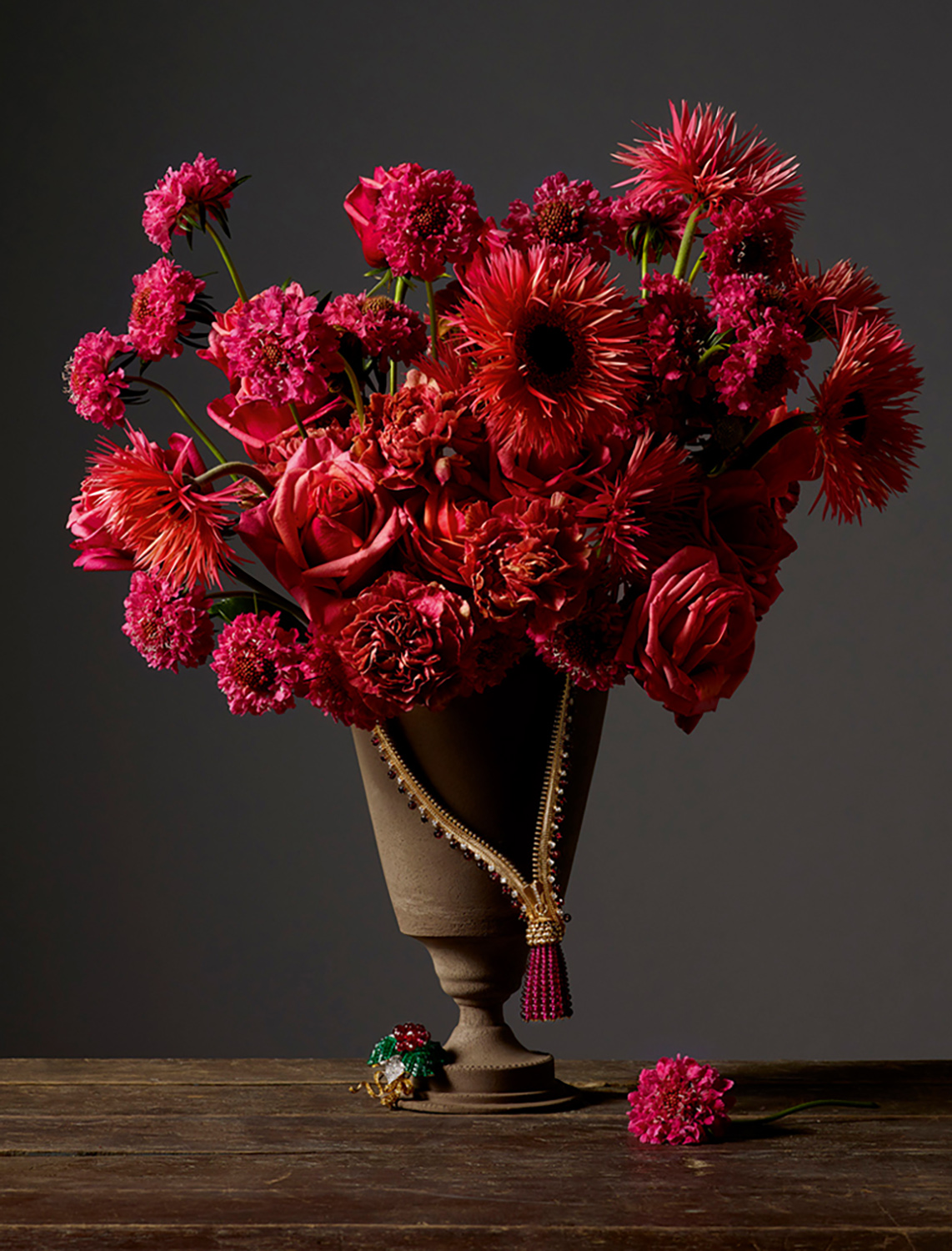 KMA photographer Isabelle Bonjean shoots photograph of red flowers and gold jewelry against a grey background for Citizen K 