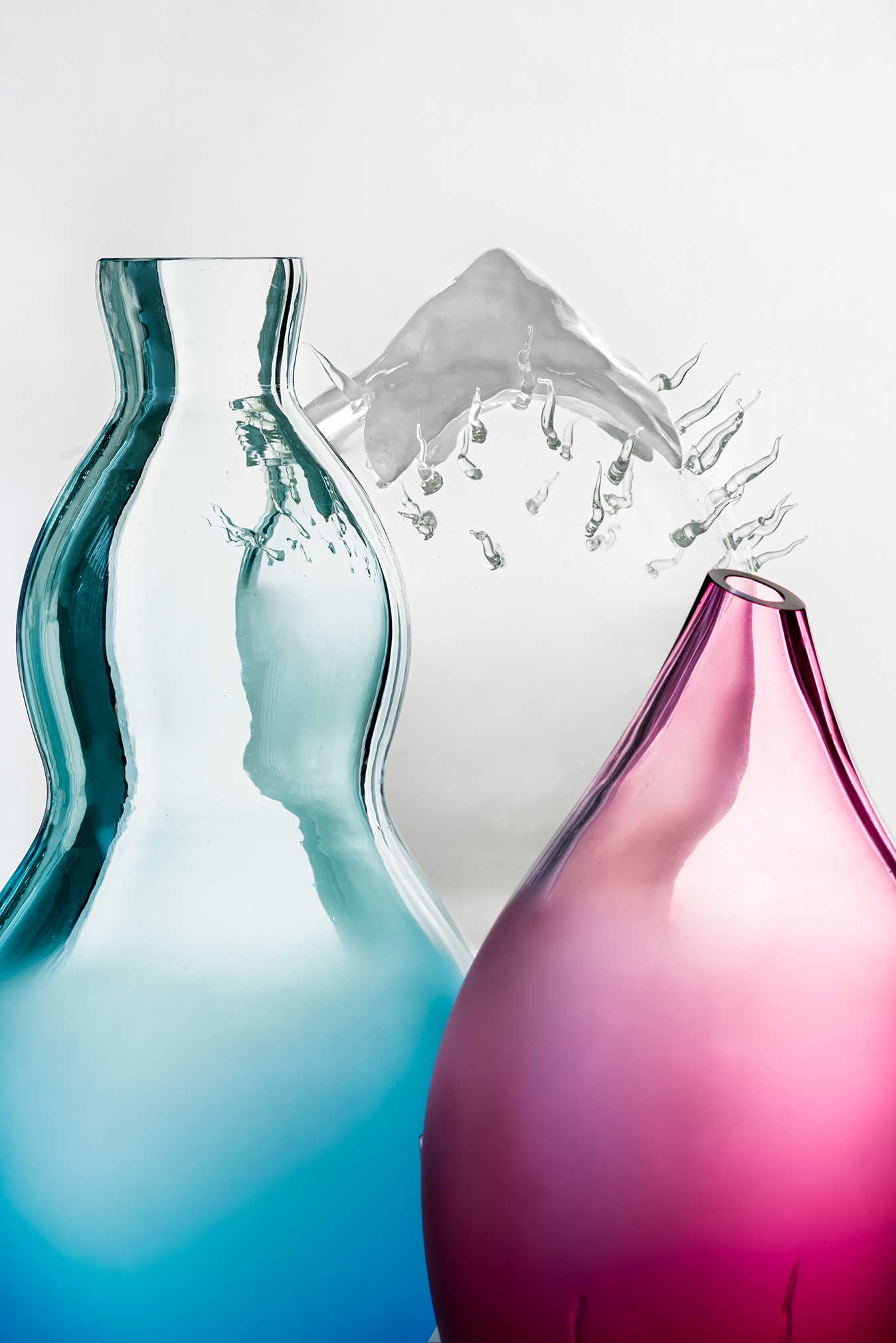 Blown glass lamps in pink, blue, and transparent hues by Plaja Studio on neutral background