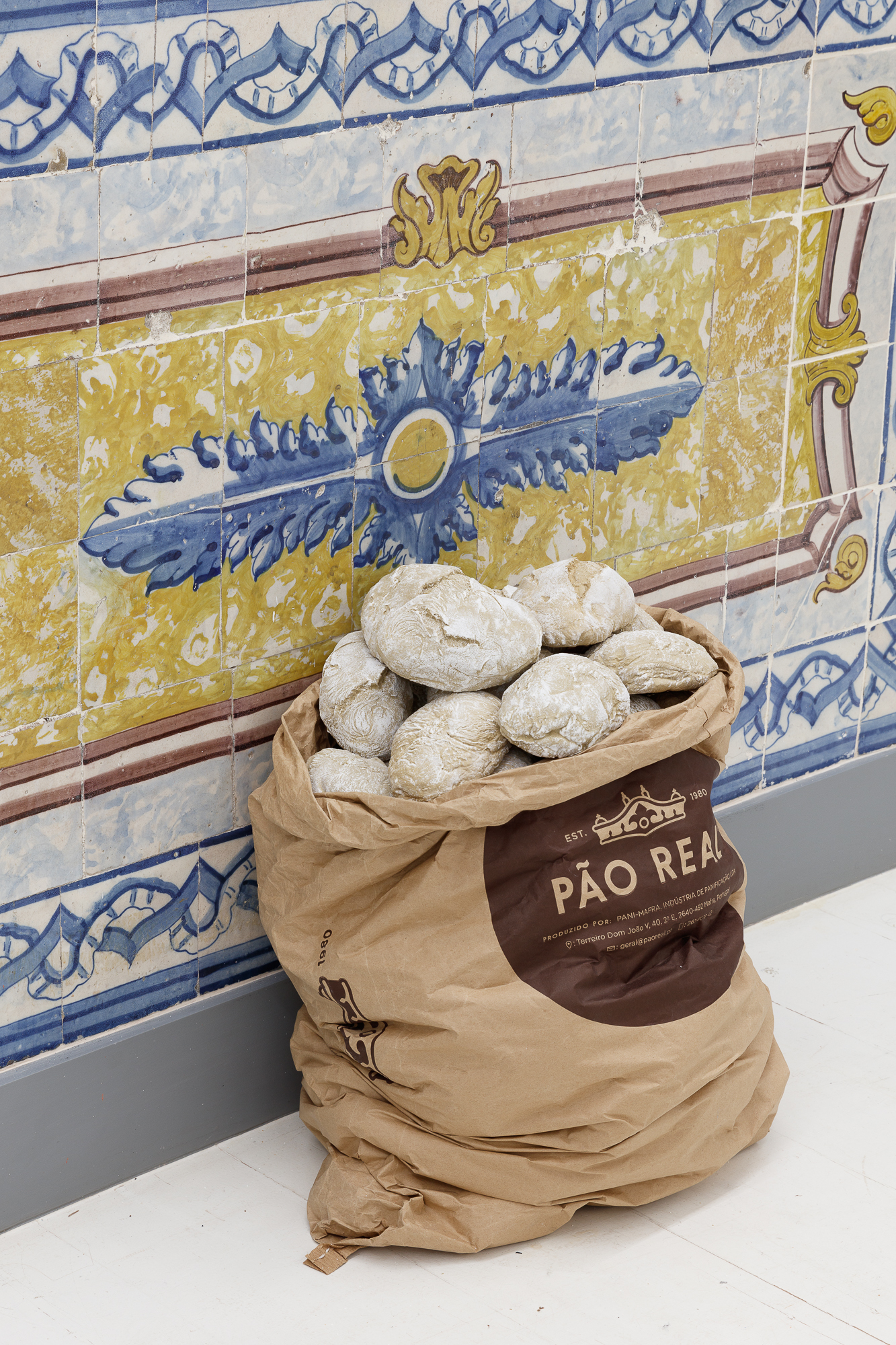 Pão Duro, 2022 (Put any importance on the nail to lift a loaf of bread). Ceramics, paper bags, nails and banknotes deposited by the public.