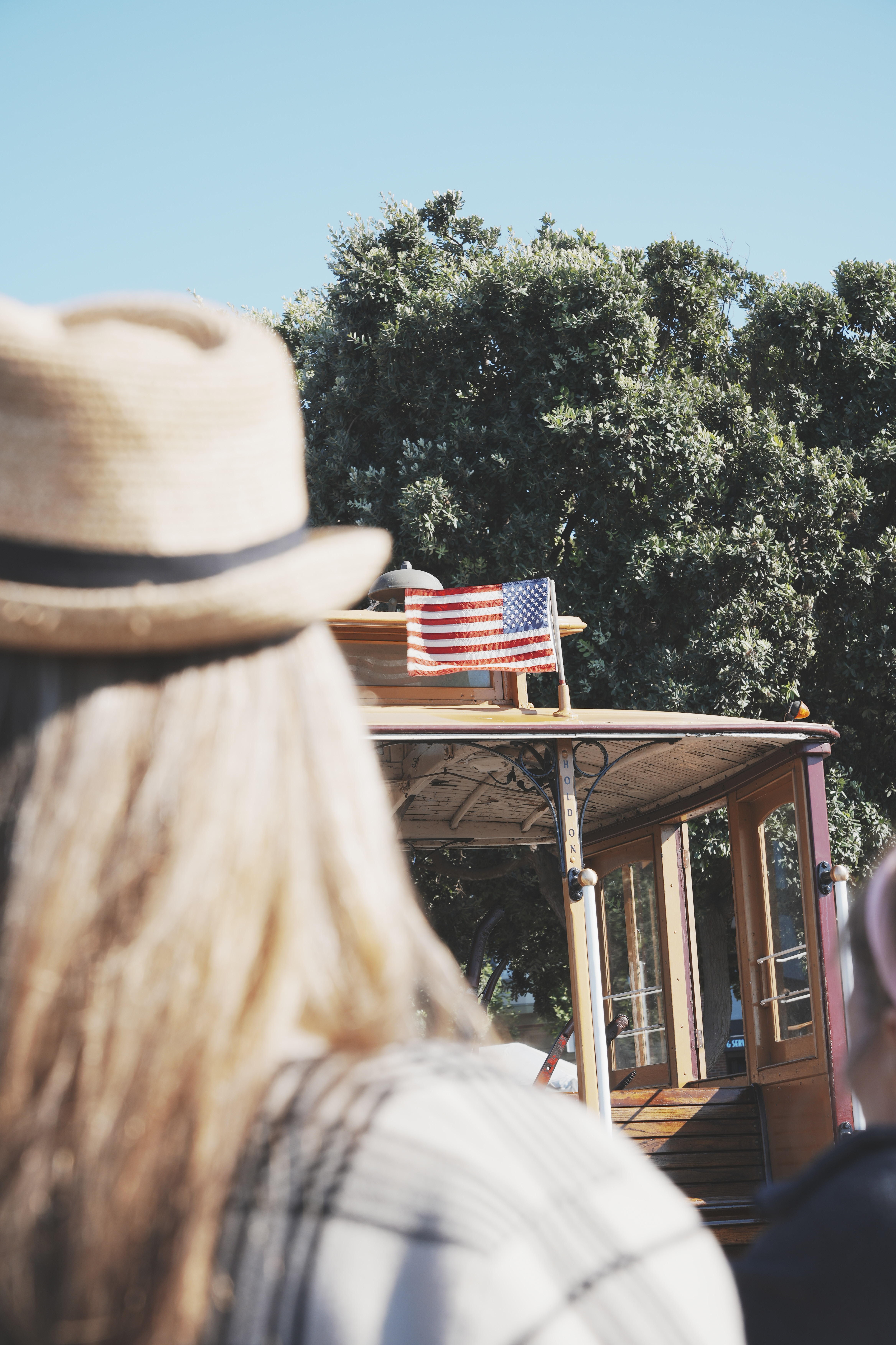 The vibrancy of the Stars and Stripes atop a cable car at Cable Car End contrasts sharply with the daily hustle of life below, capturing the dichotomy of the American experience in San Francisco.