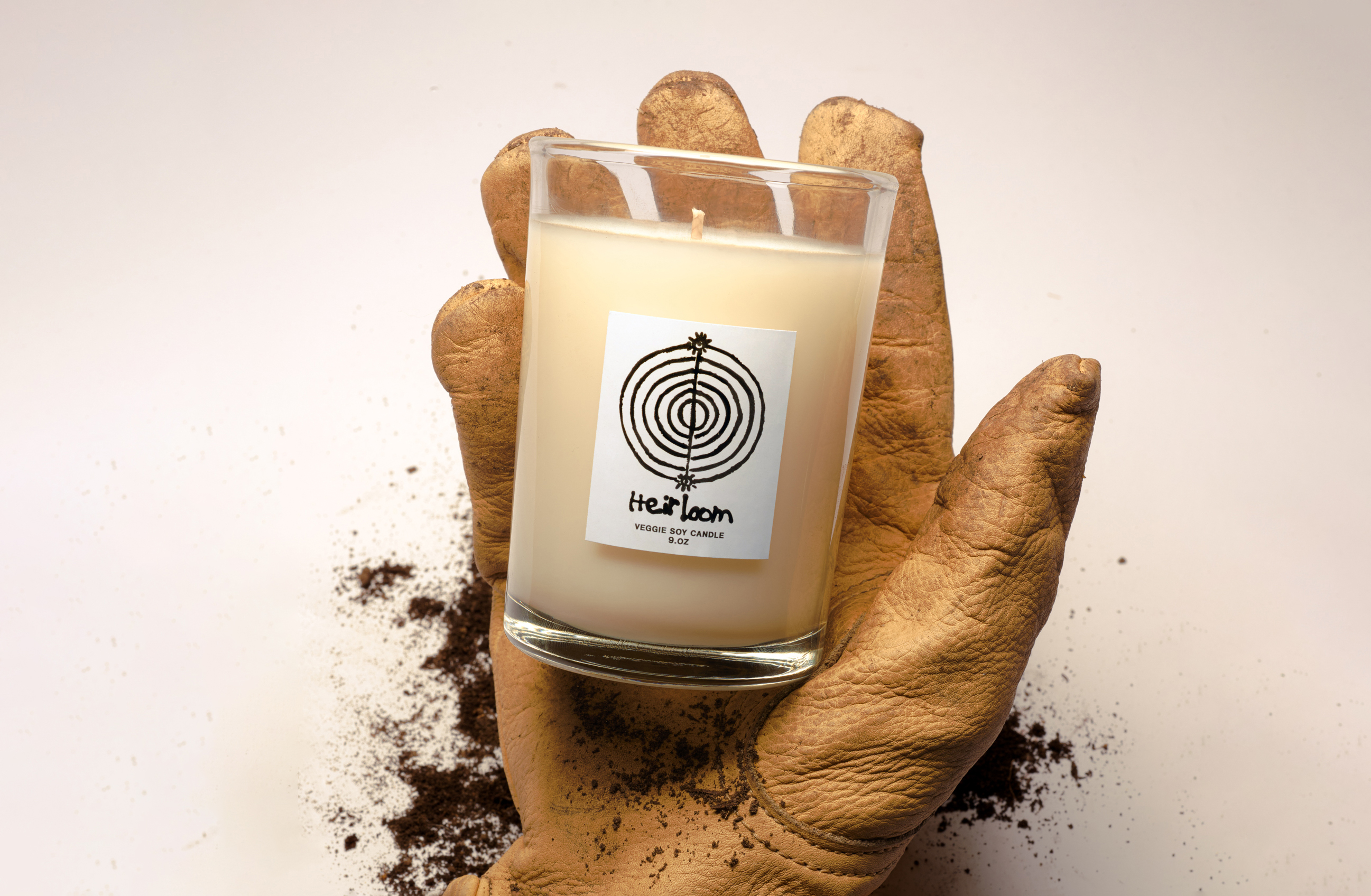 a leather glove holding a tomato and dirt