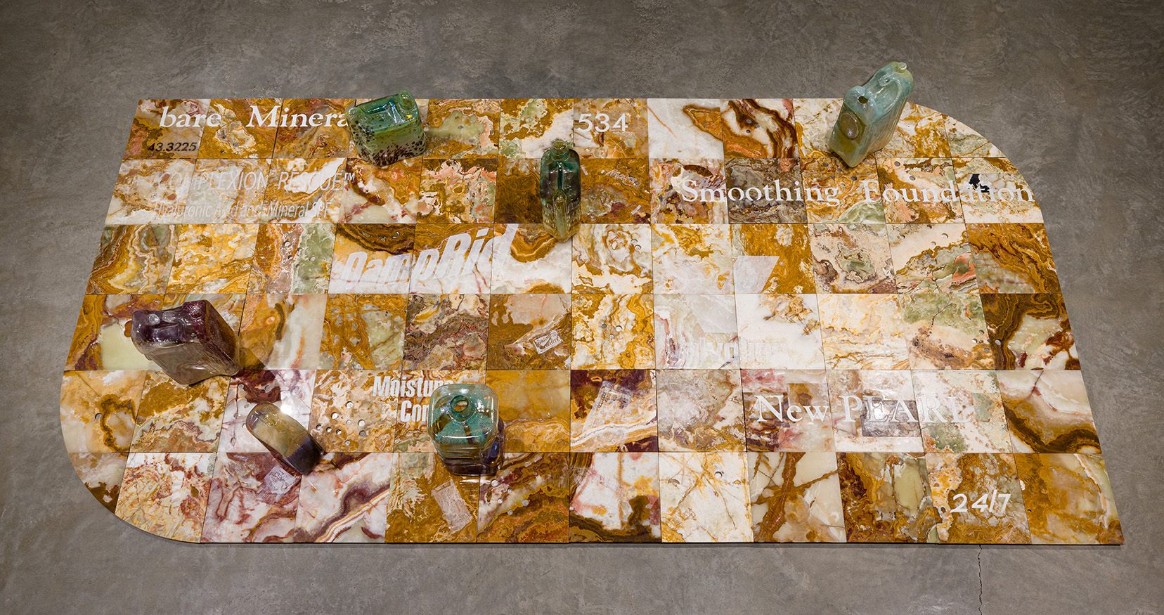 Catherine Telford Keogh, "Compost Index 3 with Volume 2.1, 2.2, 3.1, 4.1, 4.2, 5.1," 2023. Sandblasted Salvaged Multicolor Onyx Tiles, Waterjet Salvaged Italian Marble Tiles, Mold Blown Glass CLEARA™ H2O Filter System Dispenser, Mold Blown Glass Super Tech Full Synthetic SAE™ 5W-30 Motor Oil, 5 Quarts, Mold Blown Glass Sun® Liquid Laundry Detergent, Clean & Fresh, Mold Blown Glass AquaNation™ 5 Gallon Water Bottle Jug, and Coins, 144 1/2 x 72 1/2  x 17 inches. Photo by Etienne Frossard.