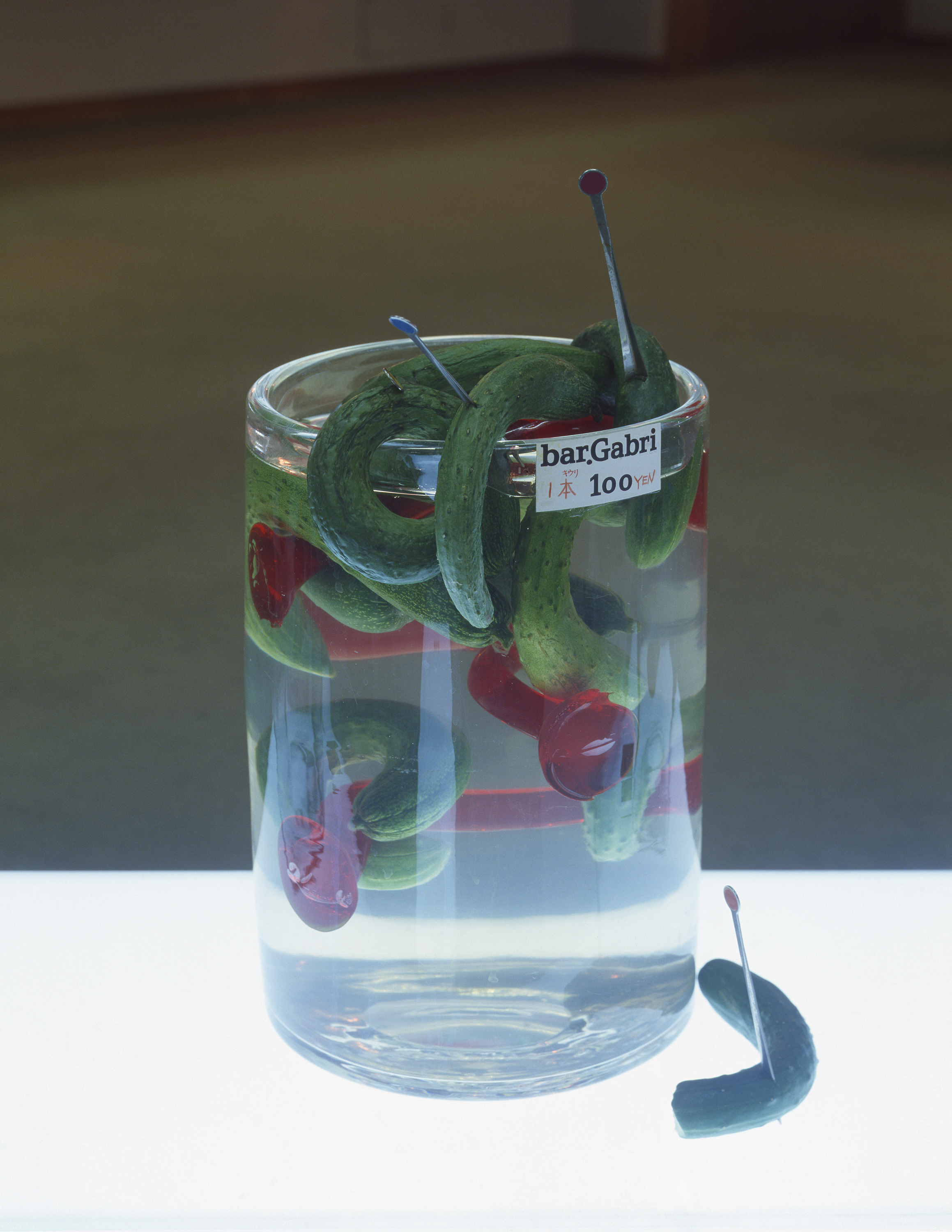 おつまみキウリ1本100円 ひねくれバーにて - ¥100 per Cucumber Snack at a Twisted Bar, June 1978, glassware made by Shigeo Fukuda, cucumber. Inkjet print, 22 x 17 in. (55.9 x 43.2 cm.). Photographer: Koichi Taniguchi.