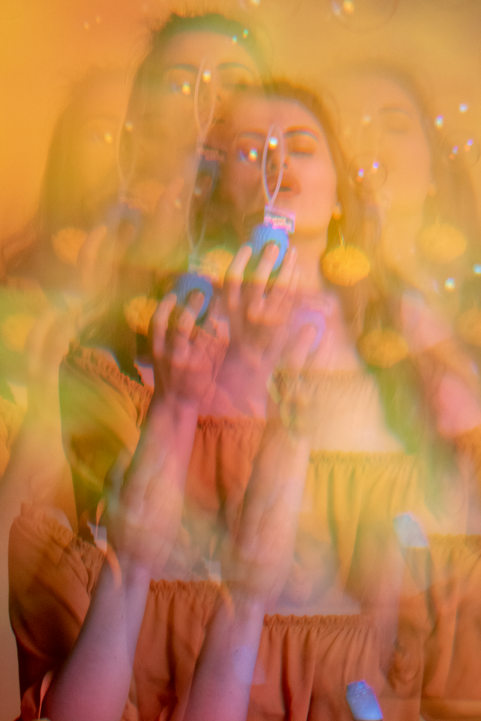 Blond woman blowing a bubble through a kaleidoscope, wearing a yellow top and surrounded by a matching yellow backdrop. The colorful and dreamy vibe gives the image a surreal and playful quality.