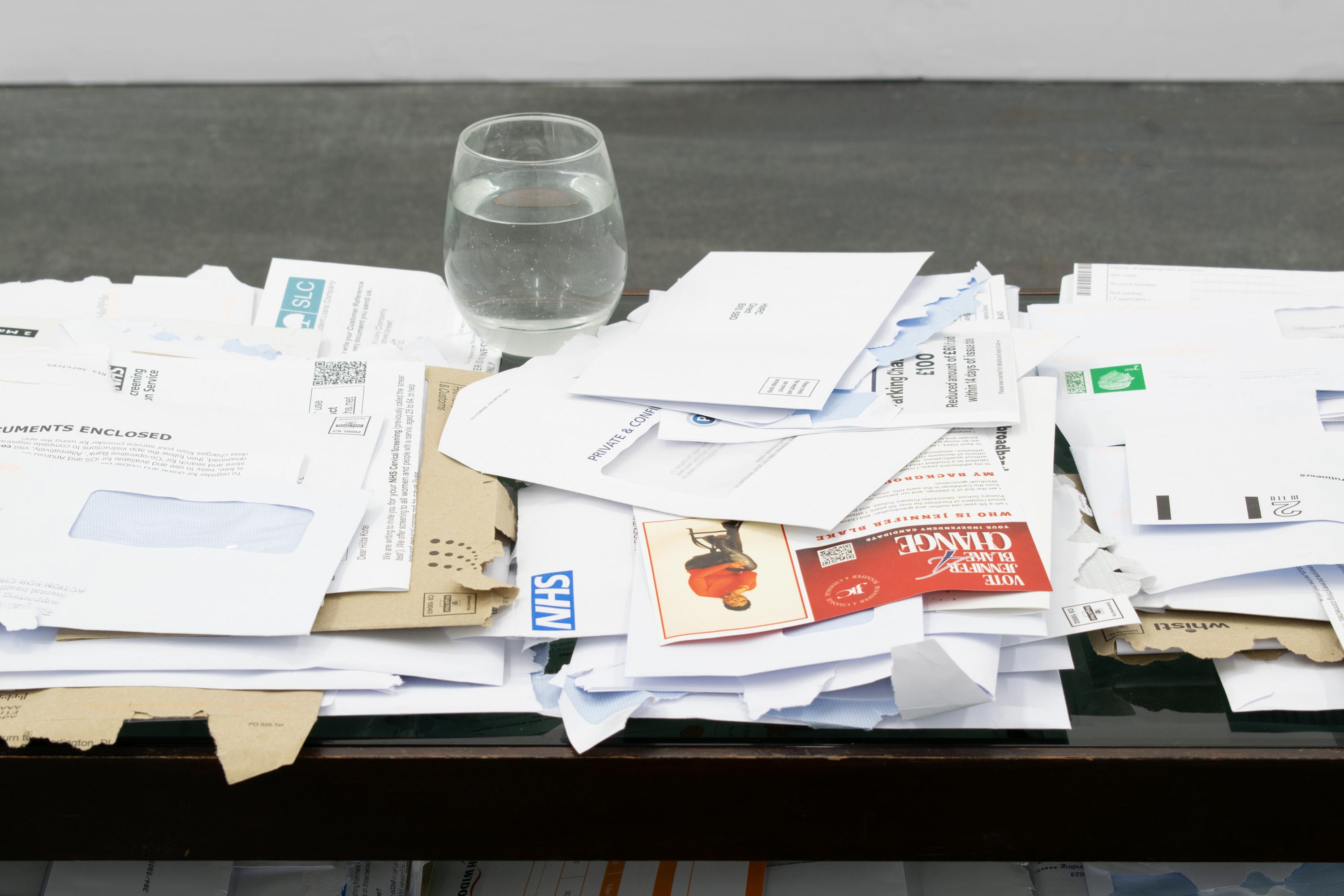 Resting place, 2024 – Open and unopen mail, coffee table, glass, tap water, 45 x 88 x 44 cm (detail)