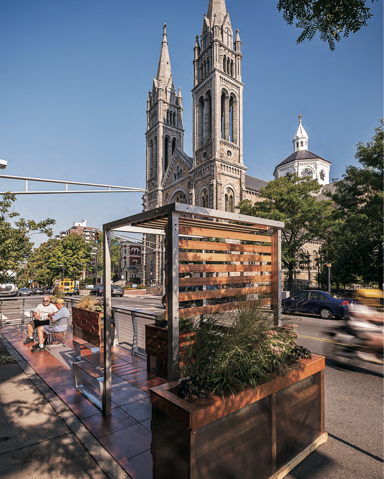 Men sit at a café table in a parklet.