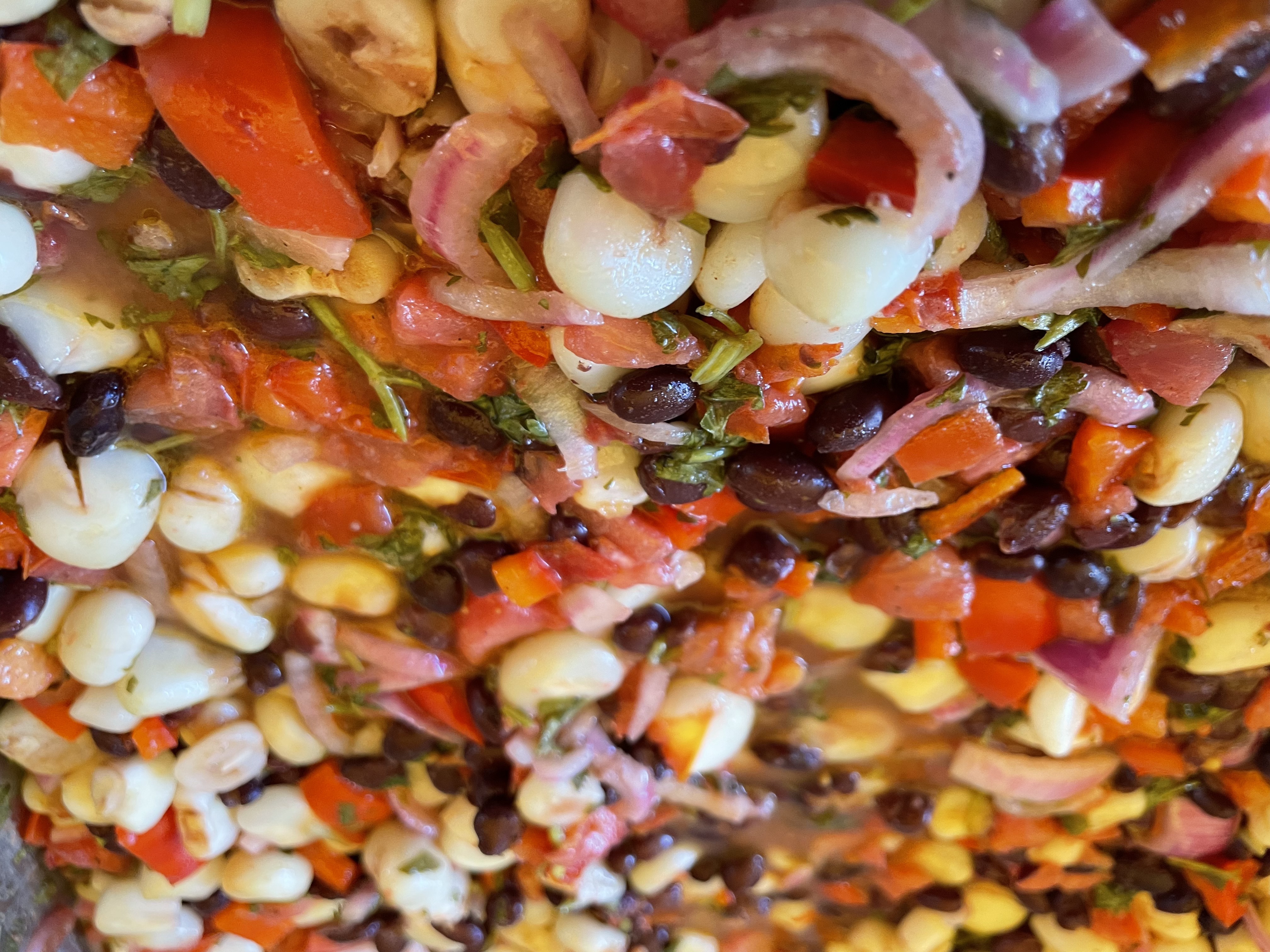 Choclo Corn Salad with black beans, red bell pepper, onions, and tomatoes accompanied by smoky paprika vinaigrette