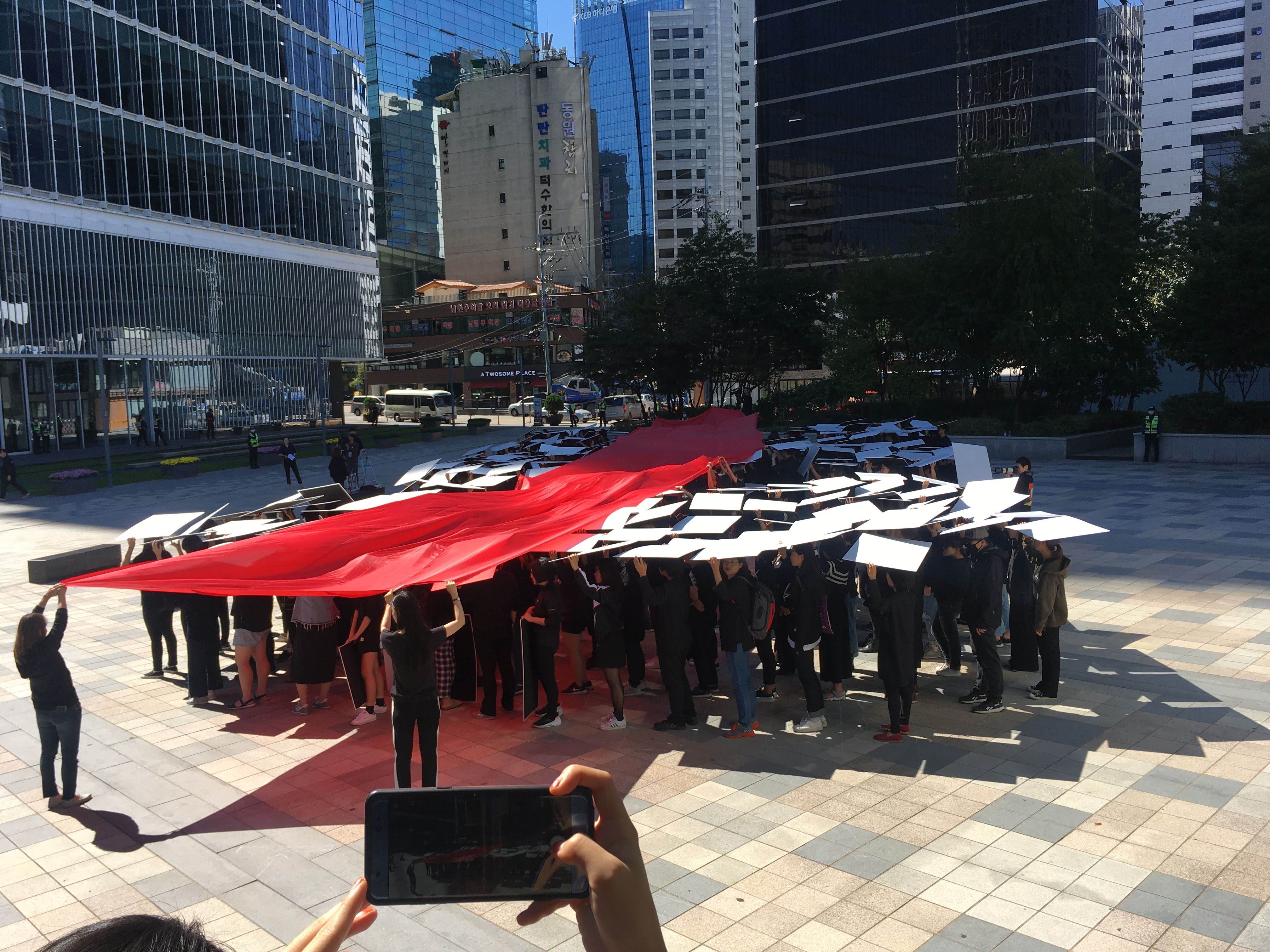 위에서 보면 269 라고 보이게 하얀 피켓을 들고 빨간색 굵은 선으로 269를 가로지르는 퍼포먼스