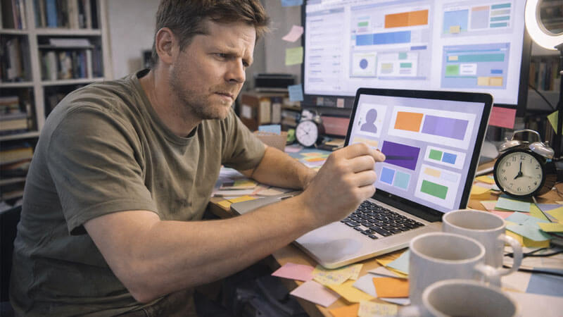 A founder in a messy home office surrounded by 47 open tabs (abstract), alarm clocks, coffee cups, and sticky notes — desperately resizing a box on a screen.