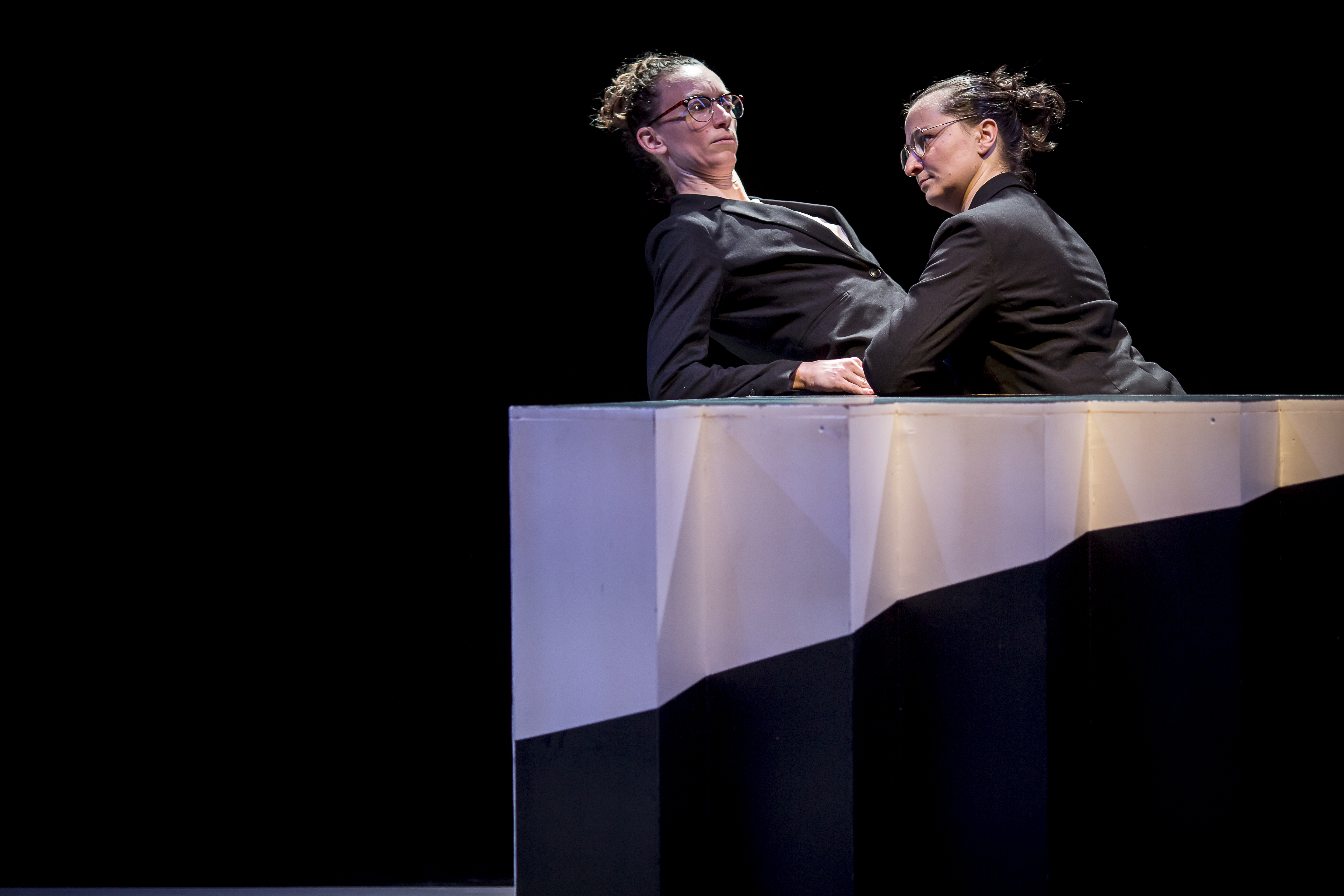 Image 9 of 10: A confrontation between two women in black skirt suits