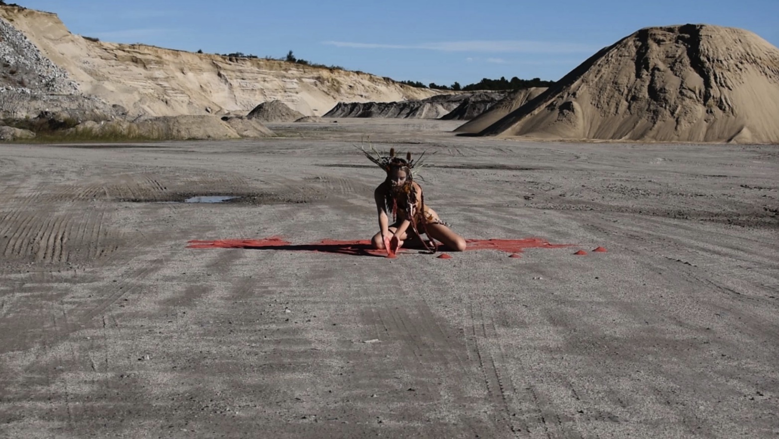 Still from Extraction2022, video, performance, dyed red salt, headpiece made from chicken wire and dried and alive flowers
