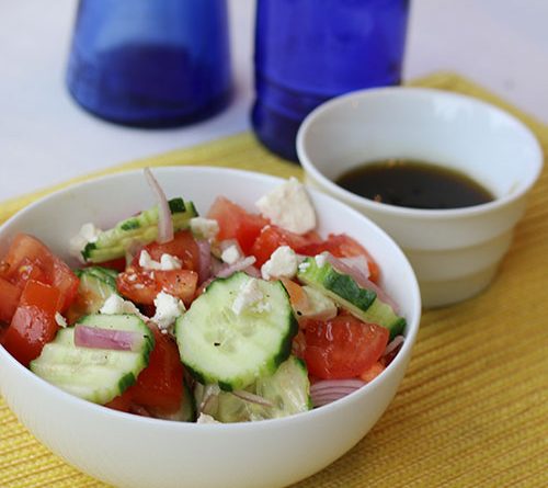 A fresh cucumber and tomato salad in a white bowl which provides good contrast with the color of the vegetables.