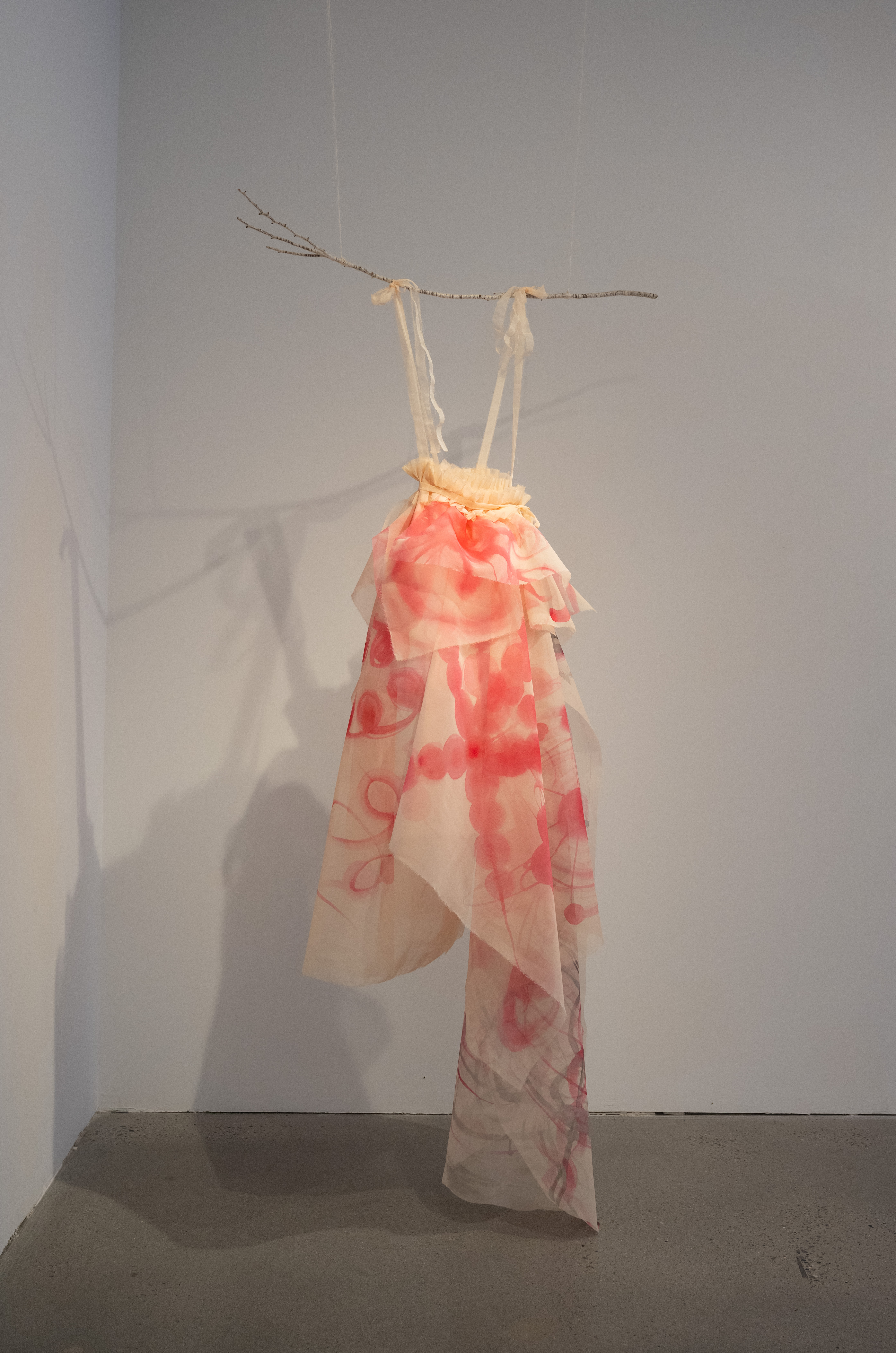 First Bloom, 2025, Korean pigment on organza silk, garment making referencing Hanbok, installation with branch, 83 x 47 x 20 in 