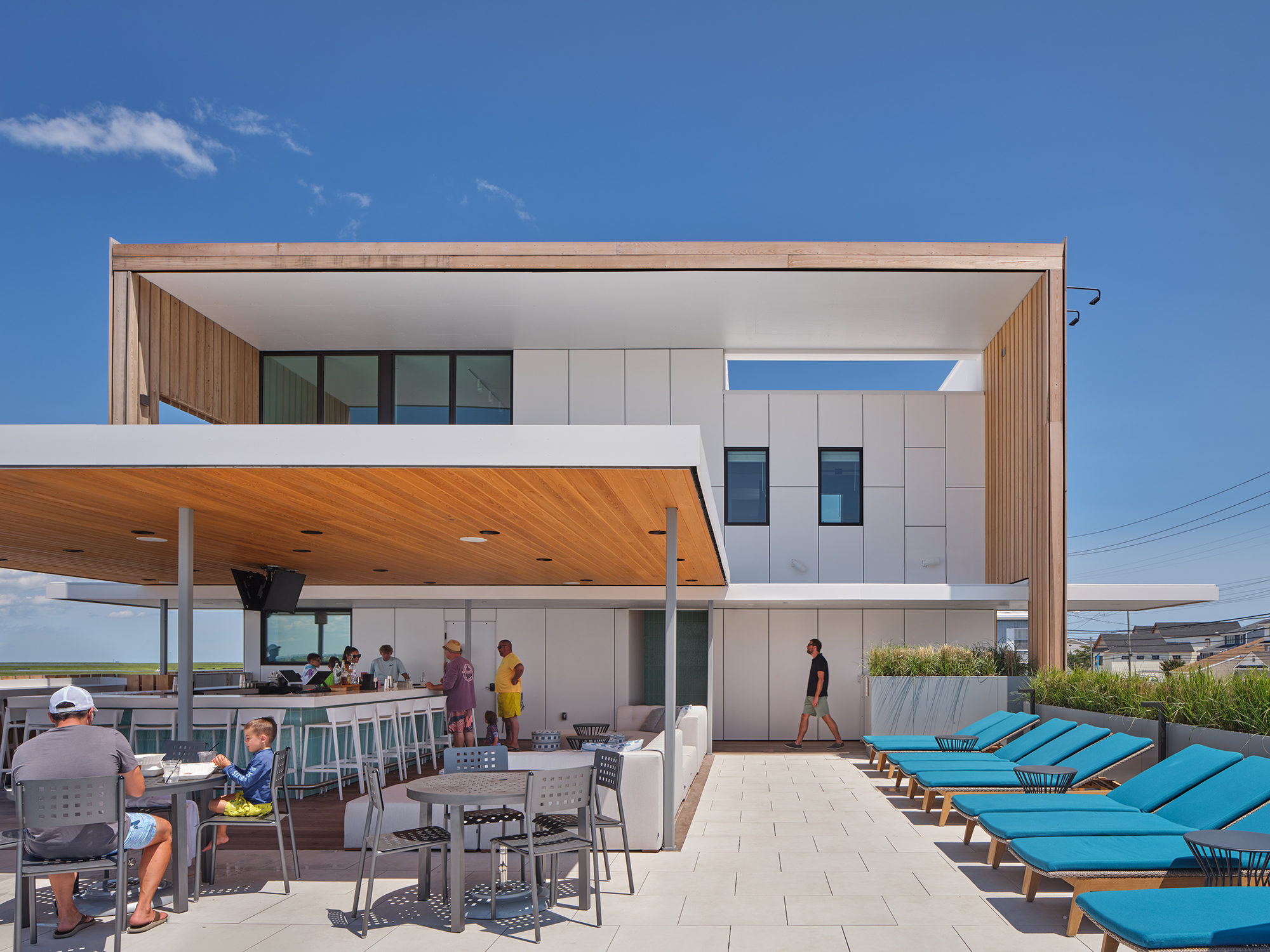 Exterior photograph of the Brigantine Marina and Paddle Club terrace, showing the covered bar and lounge area, illustrating the simplicity and consistency of the award-winning design.