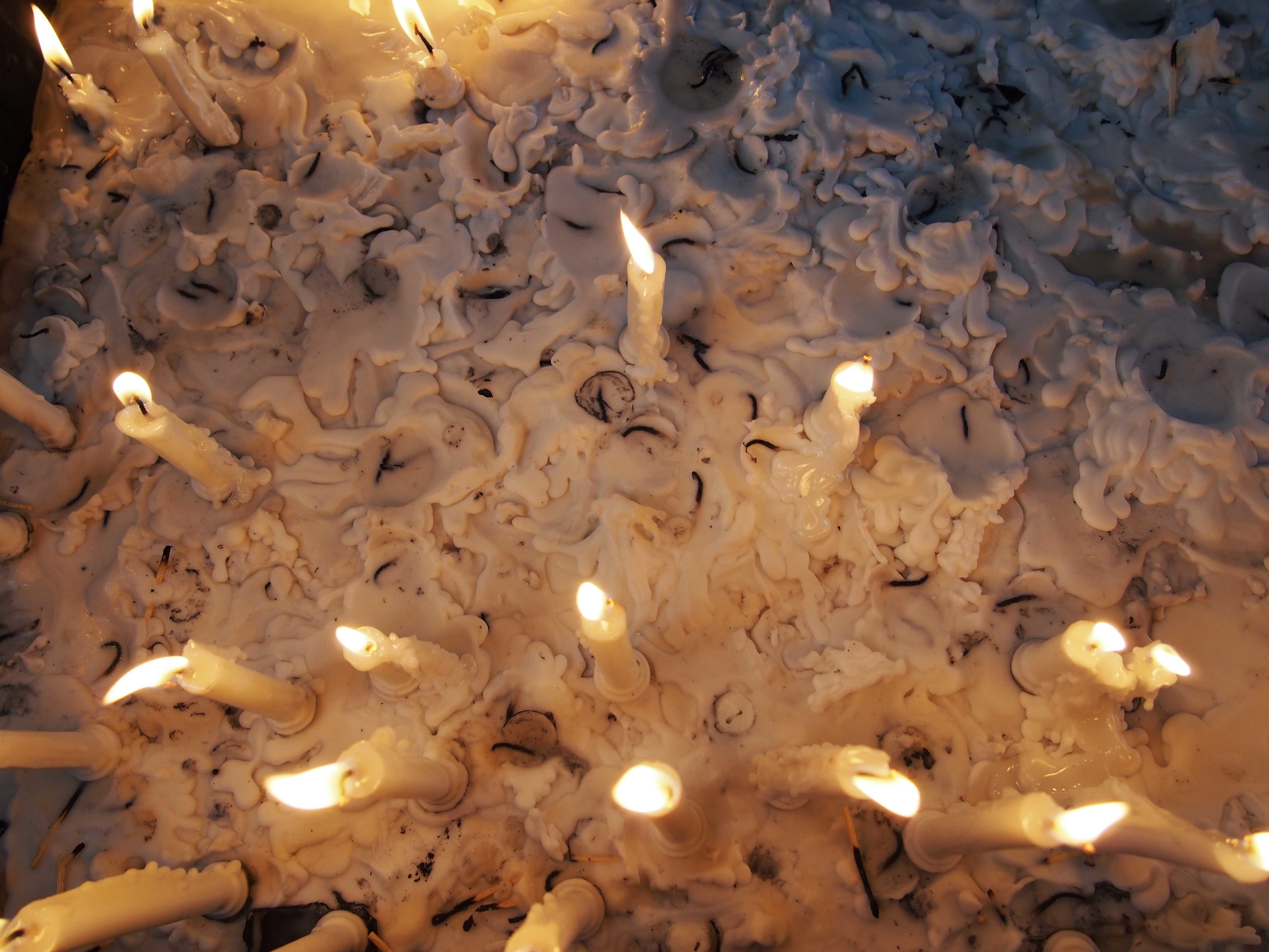 Several lit candles on a pile of melted wax. Shot from above.