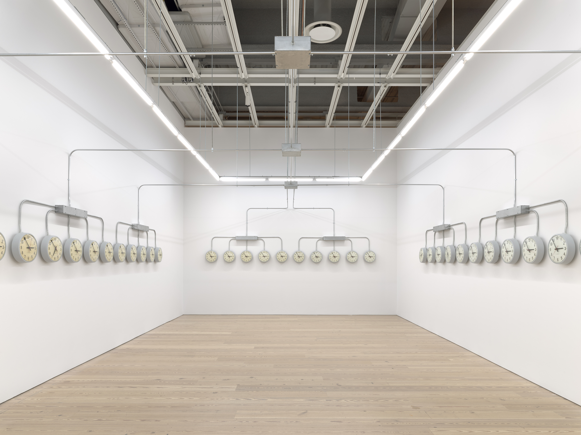 National Times, 2019, Site specific infrastructure: Closed circuit of 40 analog clocks, 1 digital master clock, sanding blocks, and electrical metal tubing. 2019 Whitney Biennial, Whitney Museum of American Art. Curators: Jane Paneta and Rujeko Hockley