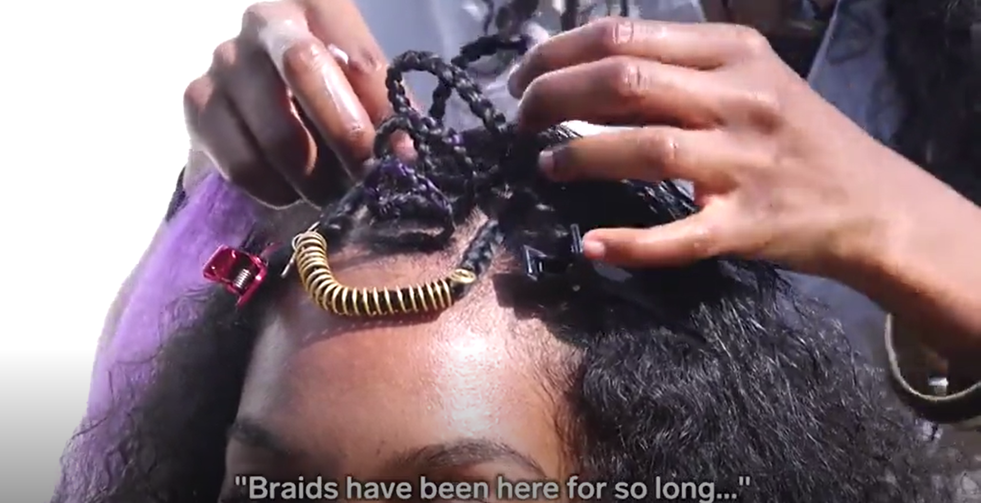 The top of a Black woman's head as two brown hands braid her hair in a traditional Ethiopian stule. Caption reads: Braids has been here for so long''