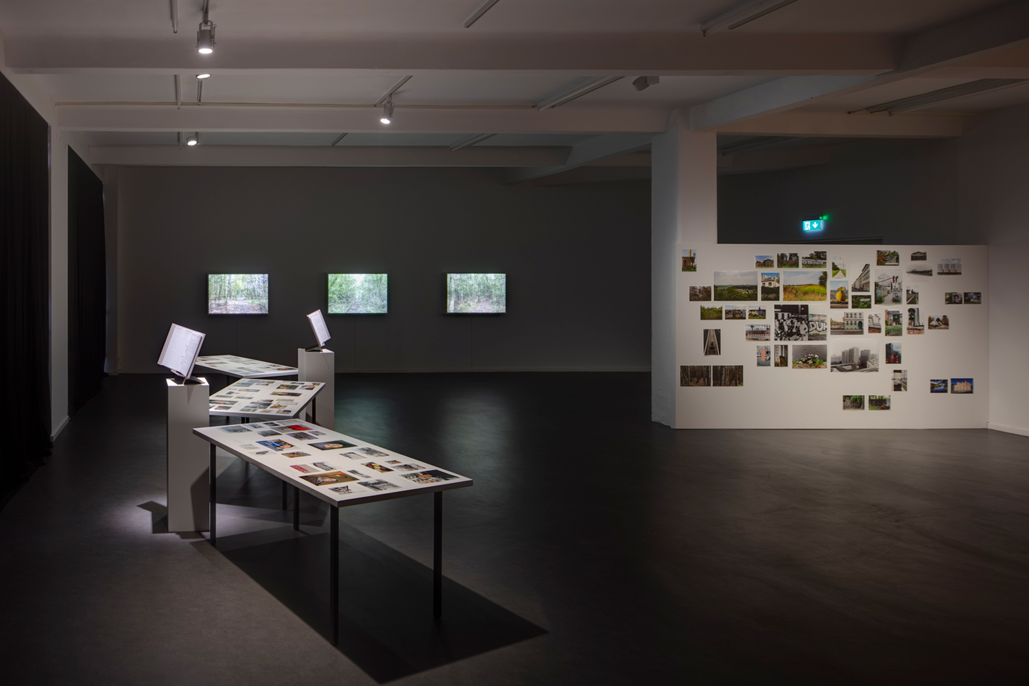 Portraits of 16 Berlin Wall witnesses and their objects on three tables (dimensions variable), 16 edited interviews in binders on pedestals; 3 lightboxes; wall with images with impressions from the Berlin Wall Trail (© David Brandt 2022)