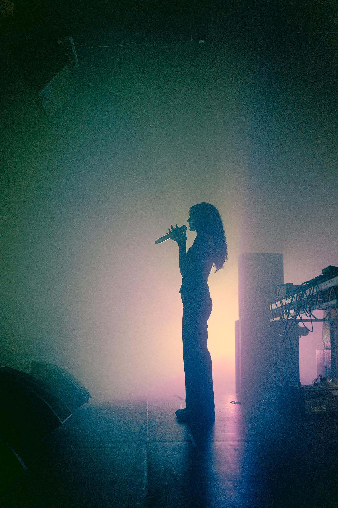 Erika de Casier performing at EartH Hackney for AVA London, silhouetted in soft pastel lighting.
