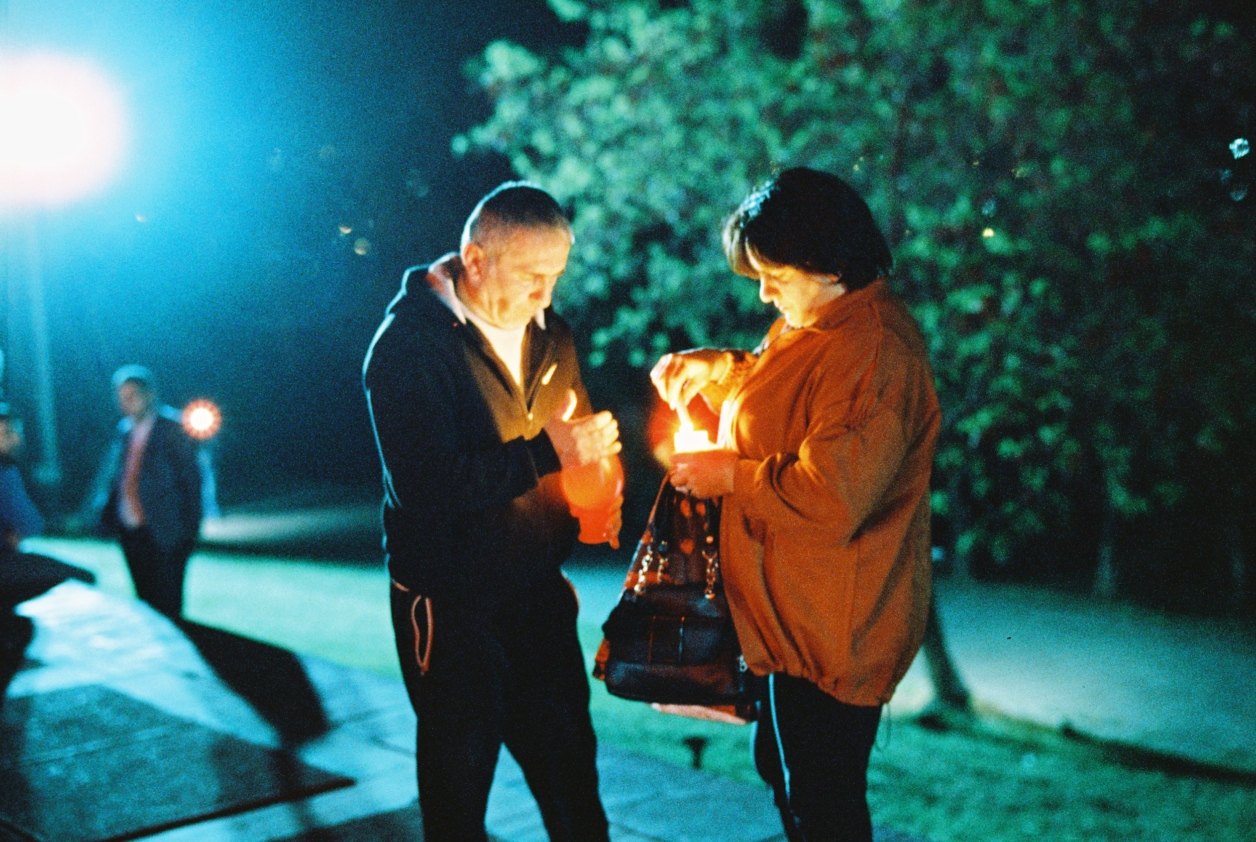 Two Armenians light candles in remembrance. Cinestill 800T.