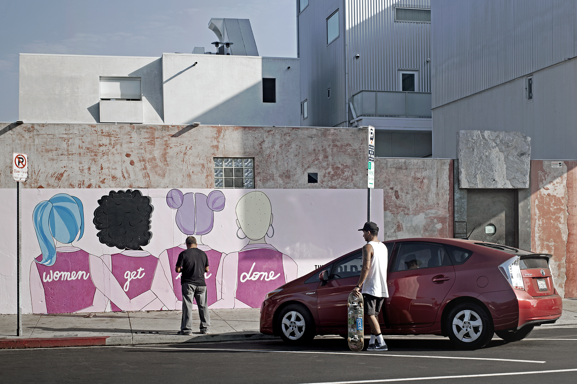 Two men and a hybrid car in front of a feminist graffitiLos Angeles, United States, 2017photography, color, single