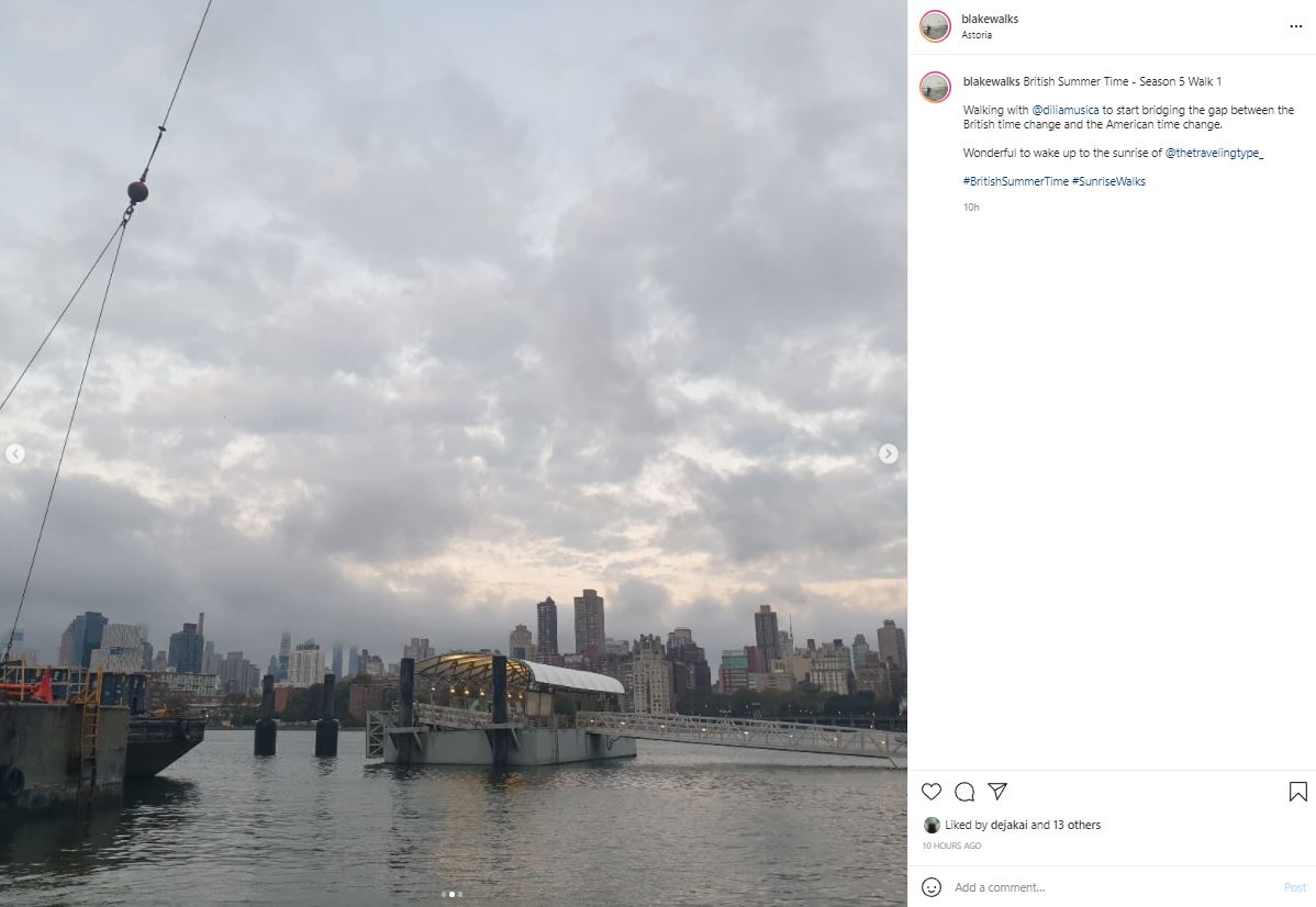 Instagram post by @blakewalks with the New York City Skyline visible across the East river, with the ferry in the middle. The sky is cloudy with patches of light visible. The text reads:  blakewalks British Summer Time - Season 5 Walk 1  Walking with @diliamusica to start bridging the gap between the British time change and the American time change.  Wonderful to wake up to the sunrise of @thetravelingtype_  #BritishSummerTime #SunriseWalks