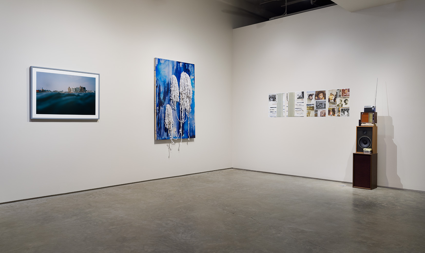 "Slippage" installation view including from left to right: Asako Narahashi, "Enoshima (from the series Half Awake and Half Asleep in the Water)", 2001, mounted C-print, 23 5/8 x 35 7/16 inches; Nadia Liz Estela, "Untitled (azúl/ni), 2021, Acrylic, ink, rope, shells, and oil on wood panel, 60 x 40 x 1 1/2 inches; Jen Everett, "Untitled (diptychs from the series Redoubled/Something We Carry)", 2018, Photo collage on vinyl, 16 x 20 inches each piece; Jen Everett, "Unheard Sounds, Come Through", 2022, Found objects, 55 x 12 x 11 inches (excluding antenna). Image by Etienne Frossard.