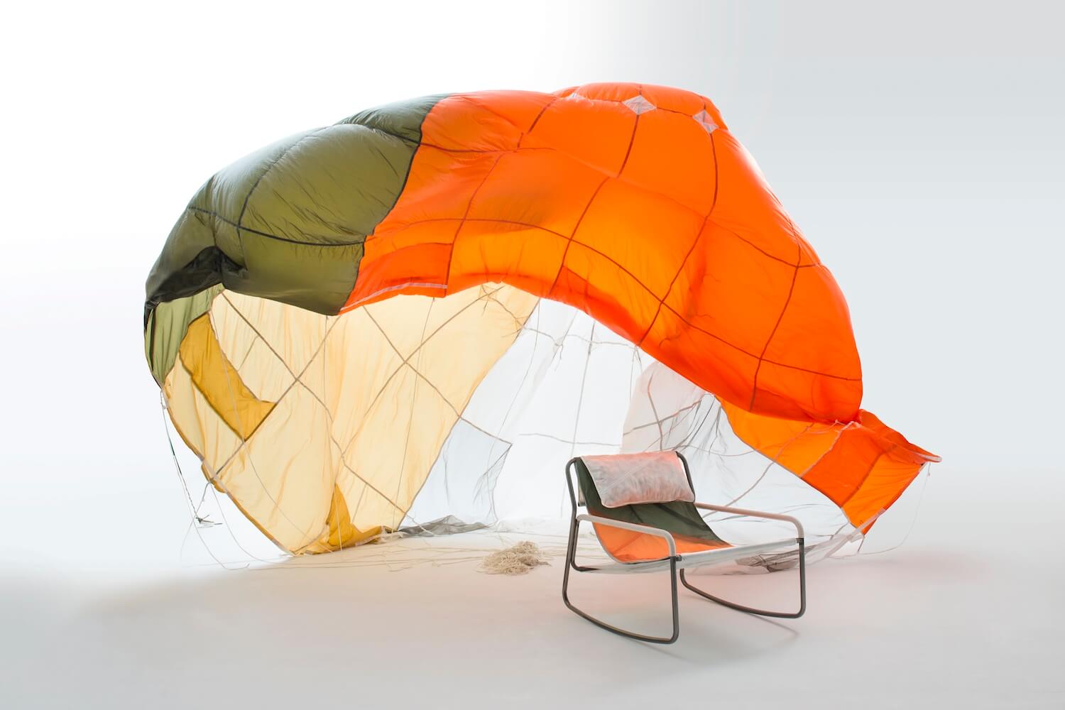A lounge chair made from parachute with an open parachute behind it
