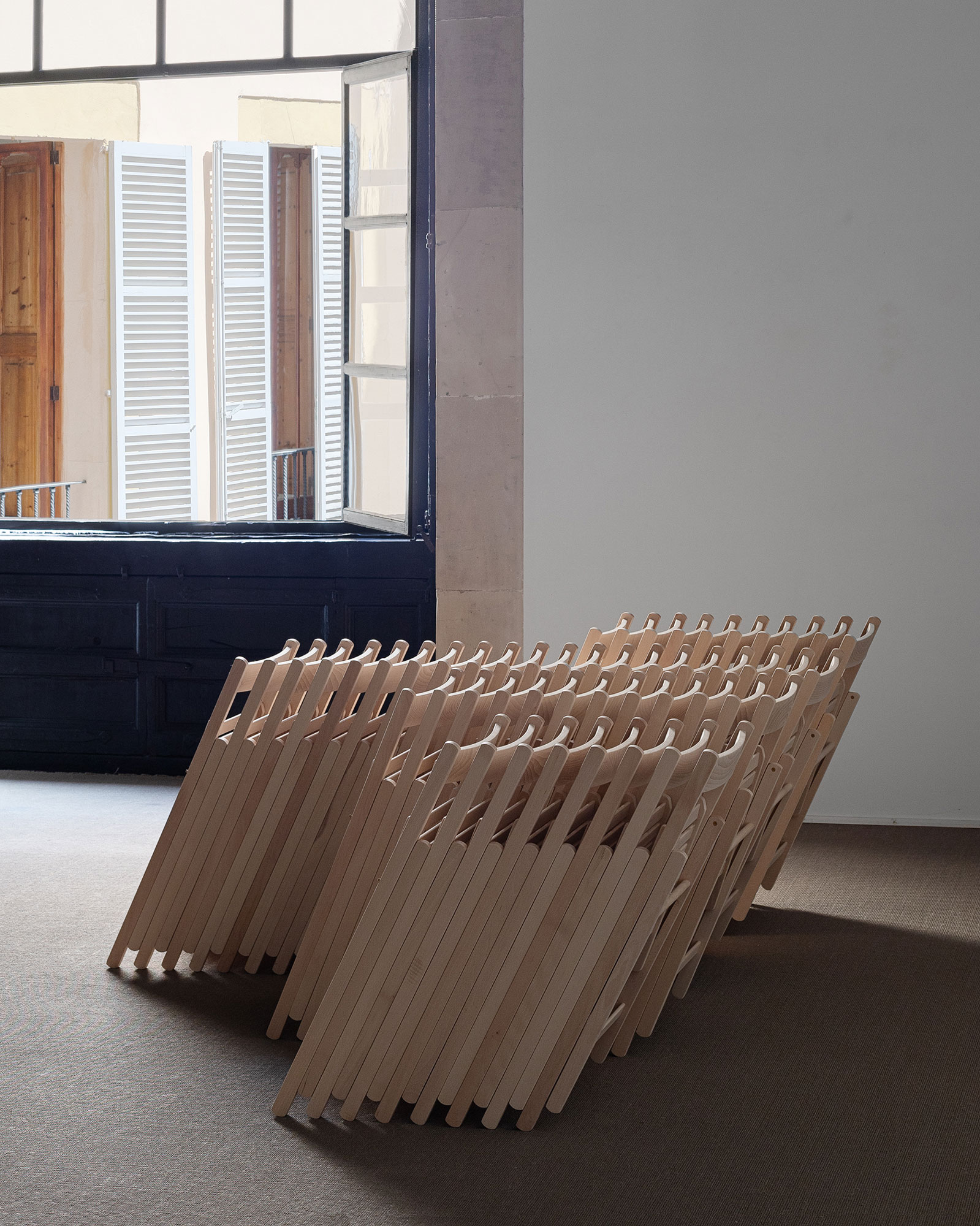 Four Freestanding Stacks of Folding Chairs, 202450 beech wood folding chairs, steel components, pine wood pegs.230 × 185 × 80 cm.Installation view at Processionària, Galeria Pelaires, Palma, 2024Photo: Juan David Cortés