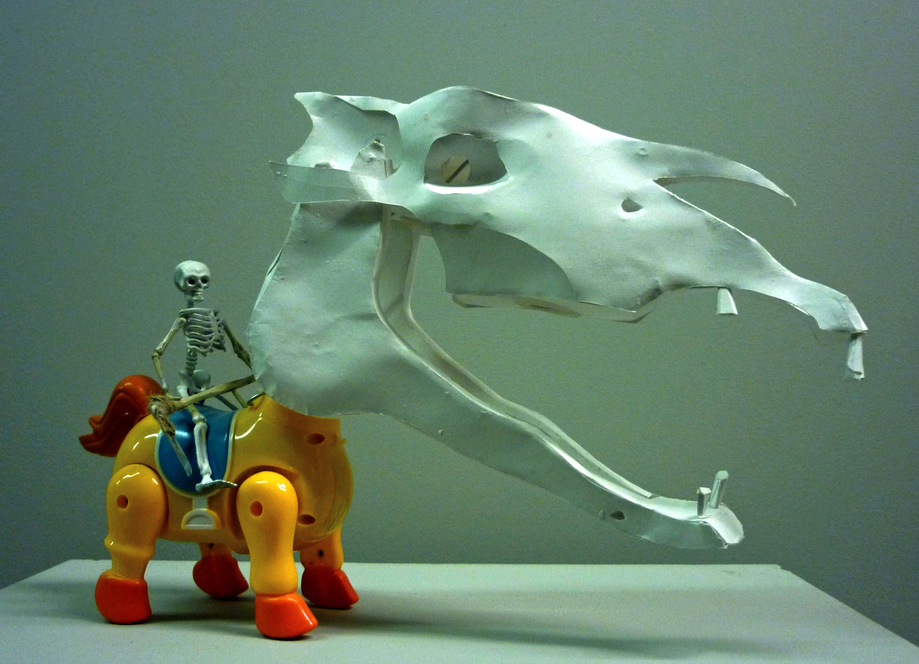 Death on Horseback. 2015. Mechanical toy horse, spray painted rubber skeleton, scalpel blade, string, pine wood, steel wire, handmade paper skull. 42 (h) x 44 (w) x 28 (d) cm.