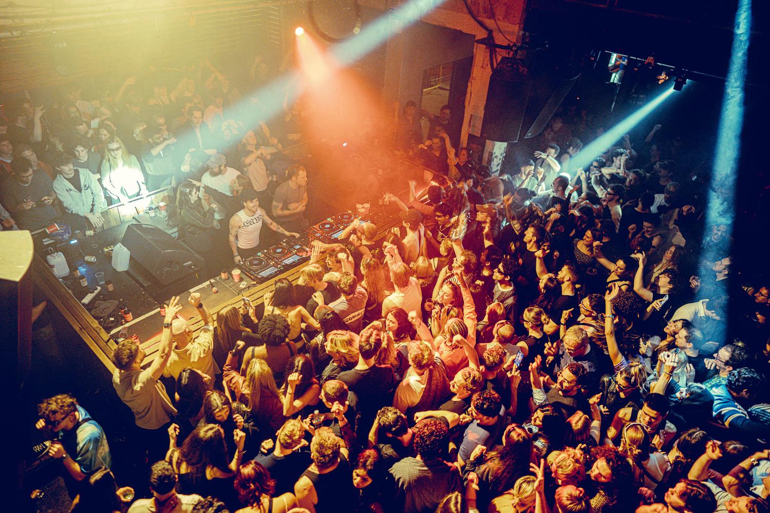 X Club performing at The Cause for AVA London, surrounded by a high-energy crowd under warm stage lighting.