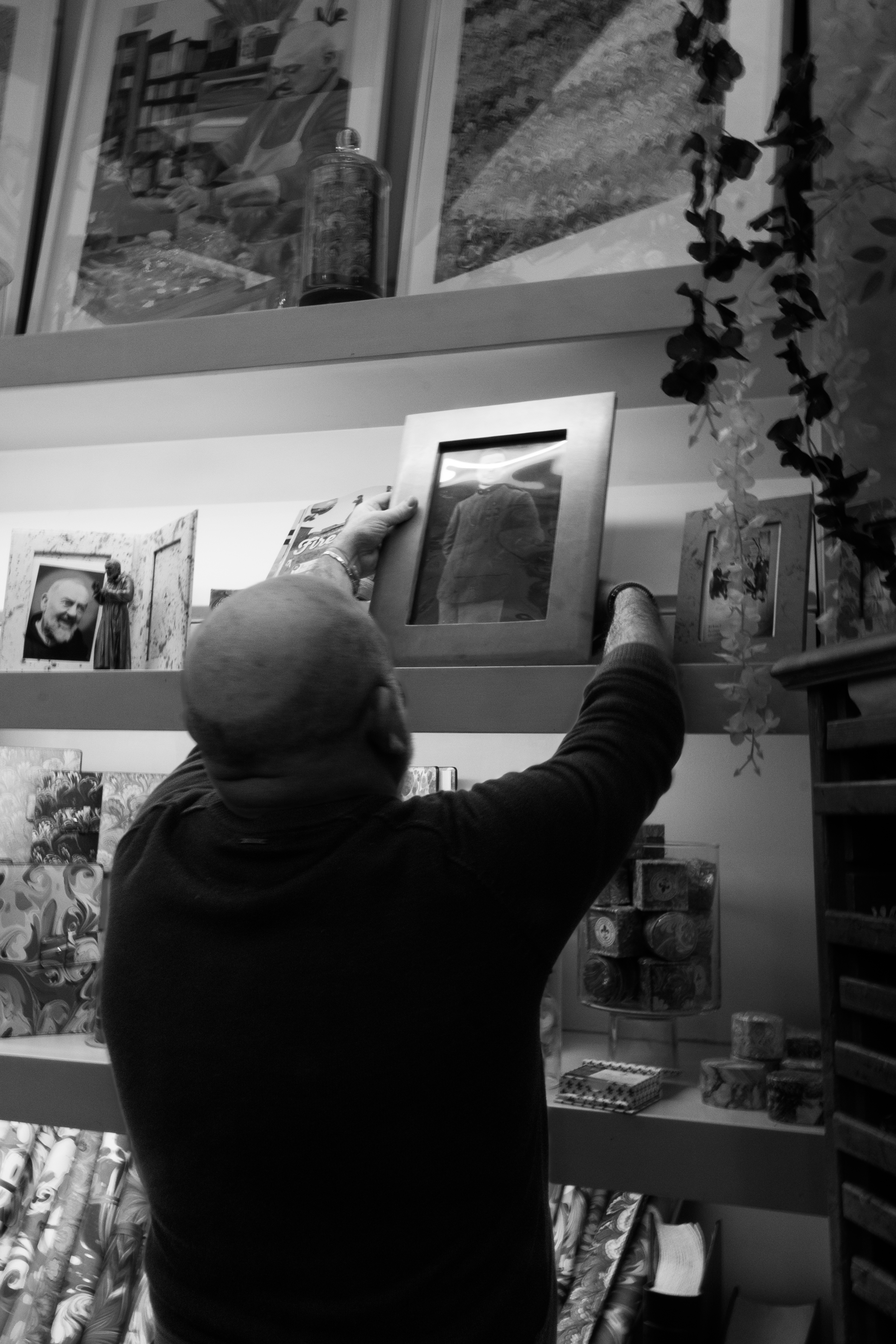 Riccardo takes a photo of his great-grandfather off of the shelf and poses for a photo.