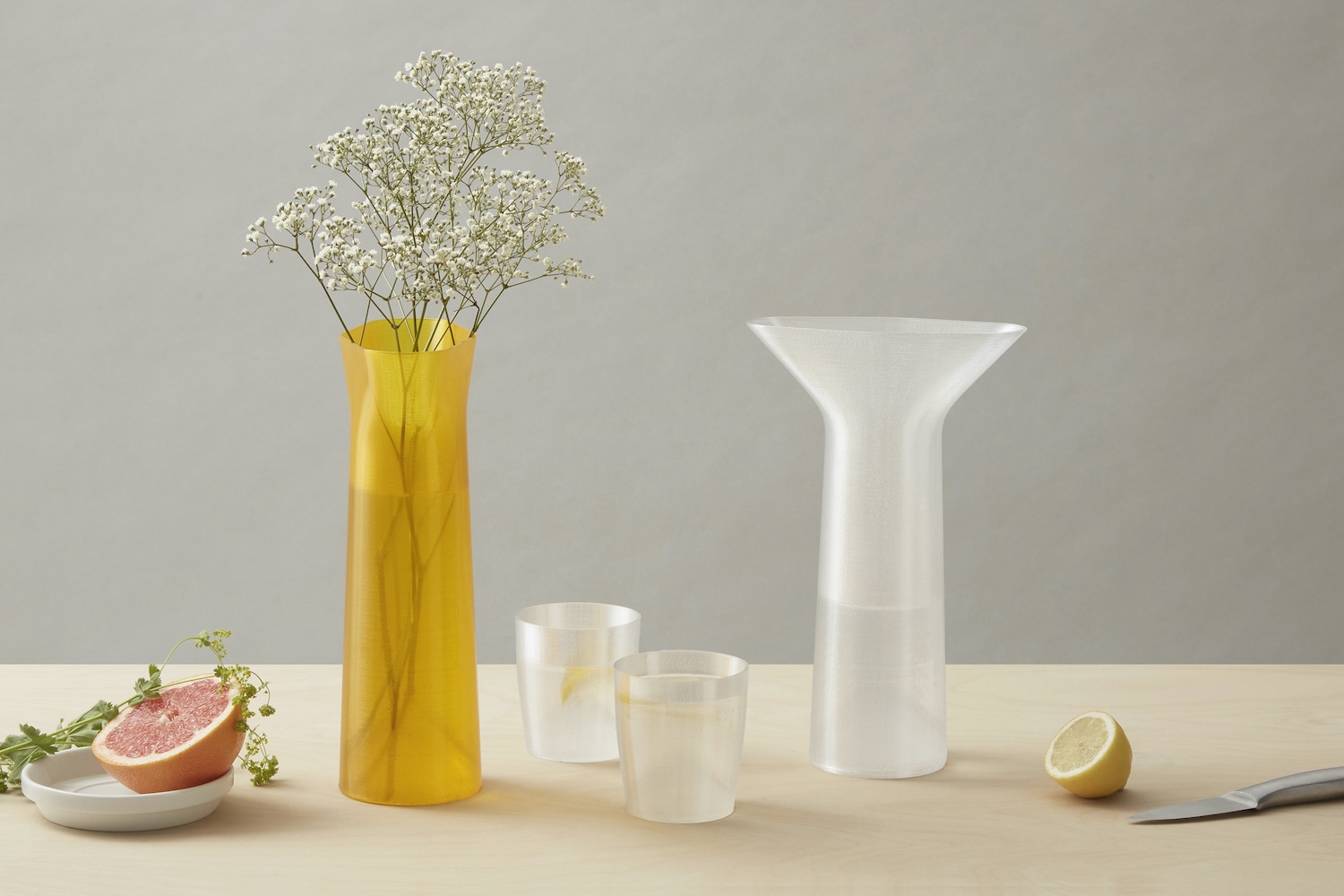 A yellow vase and white jug with glasses on a tabletop