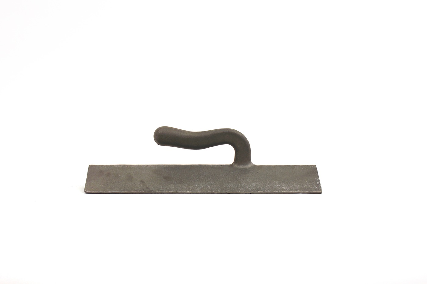 This weight was intended to securely hold a piece of flat material in place. It's large handle provides a means of transportation, and also a way to tip the weight back onto the chamfer running along the back bottom edge,  temporarily disengaging this function.  Its form and material suggests directionality and solemn, tool-like specificity.