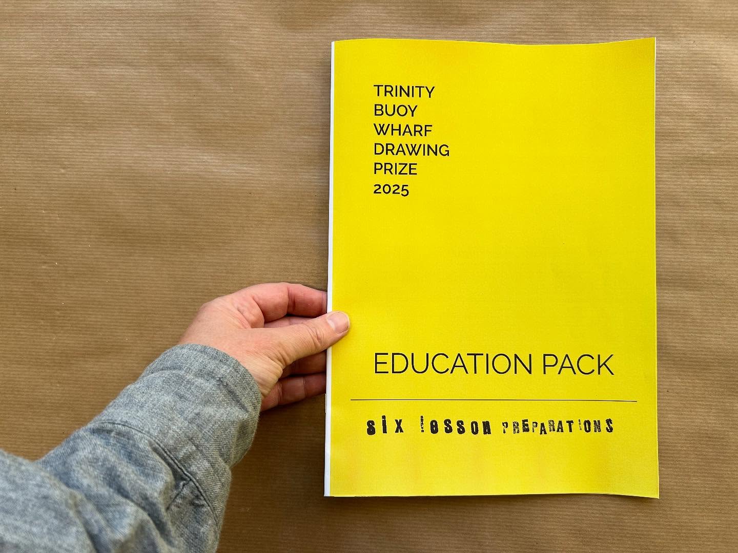 A hand holds a chartreuse yellow booklet, titled EDUCATION PACK