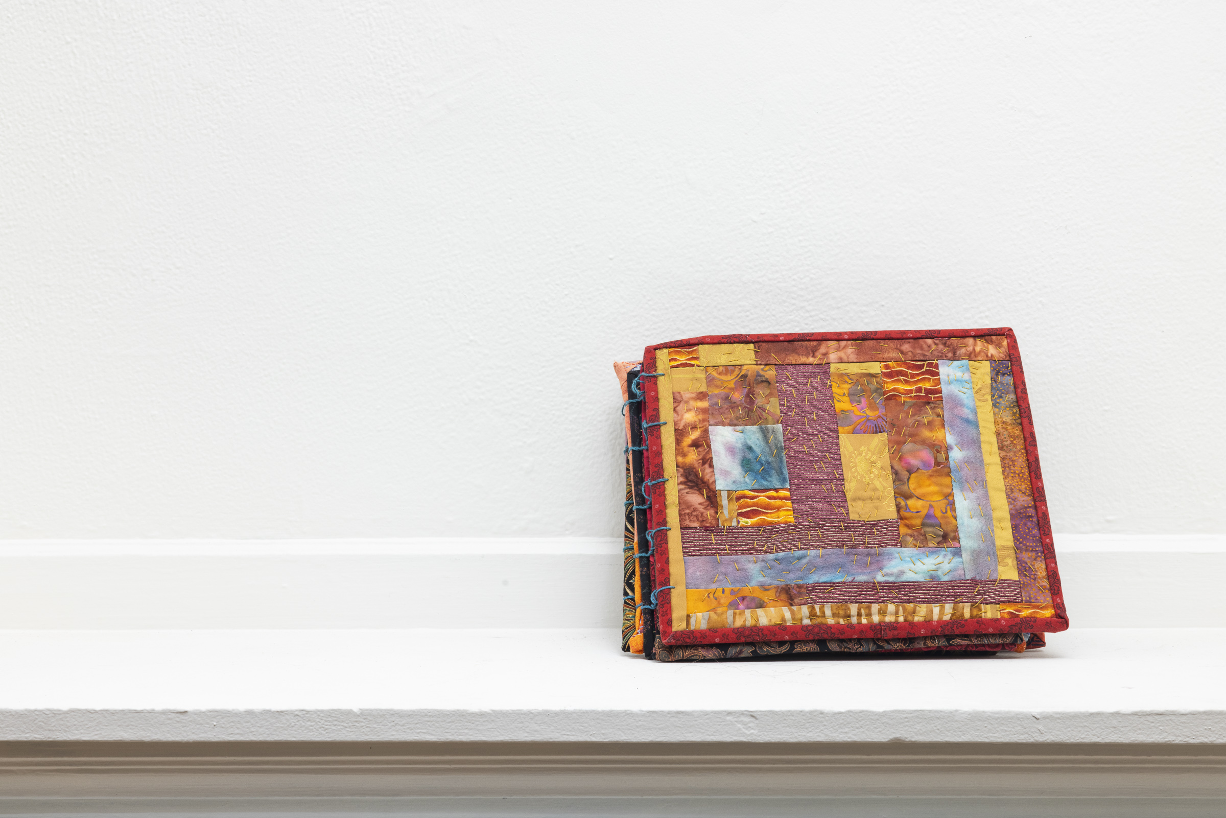 to enter commune | Cotton fabric, cotton batting, yarn, assorted metals | 22 x 10 in (open) | 2022 | Click to flip