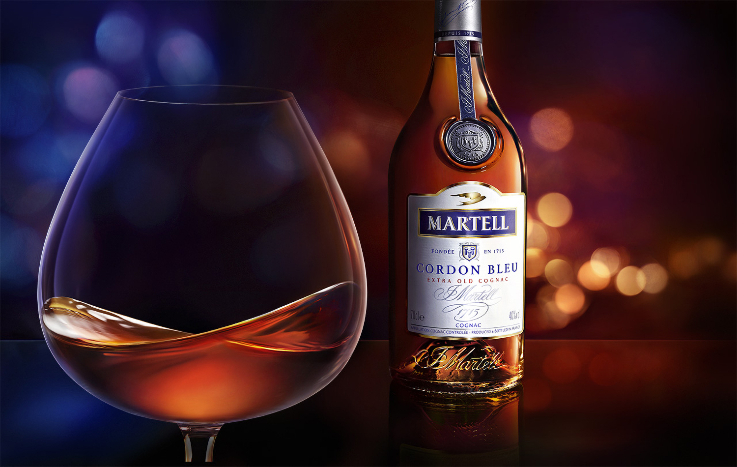 KMA photographer Daniel Schweizer photographs a glass of Martell with the bottle in the background with shimmery orange light