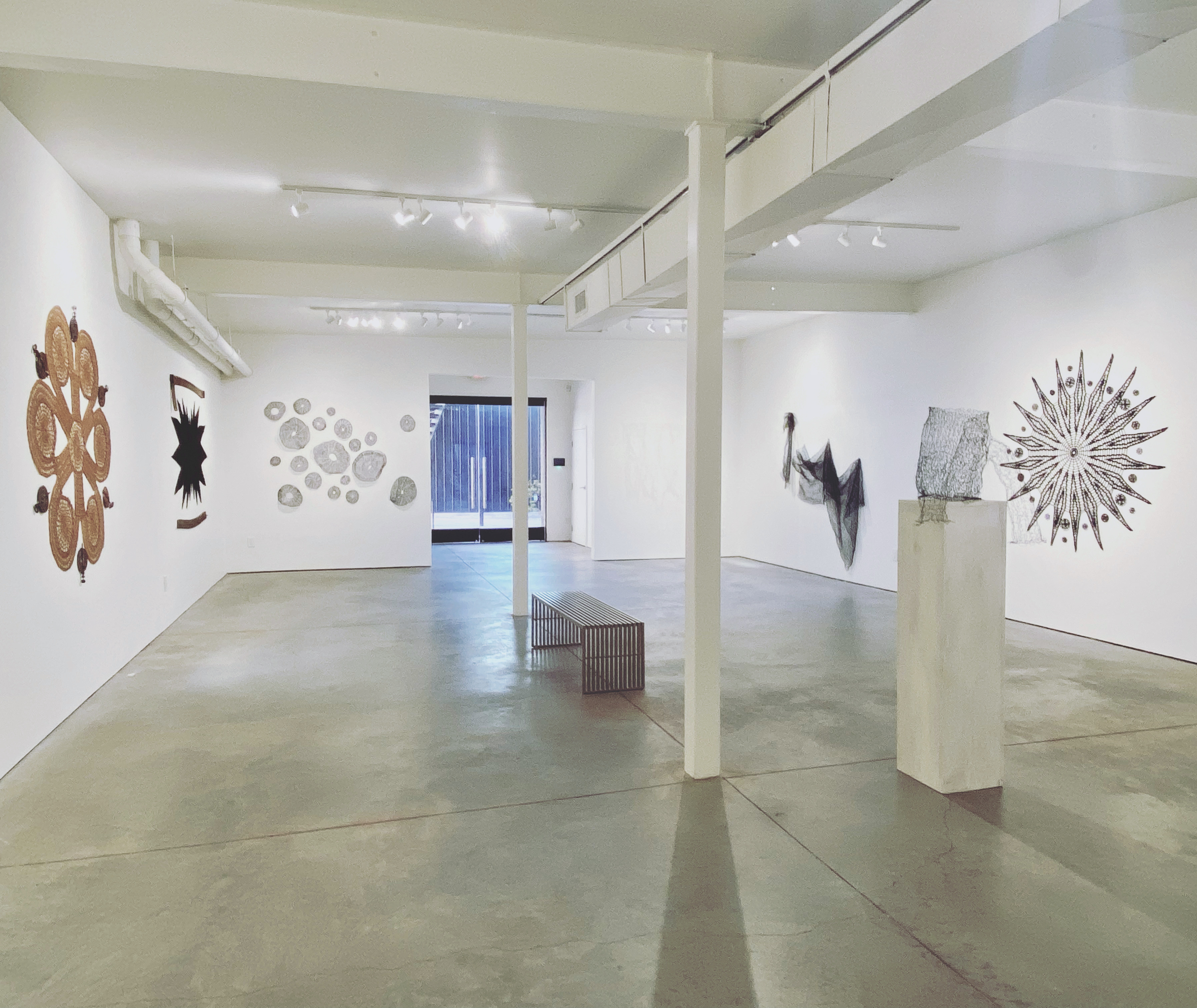 Interior view of the gallery Quappi Projects, a brightly lit white wall gallery with various wall-hanging sculptures wrapping around the room.