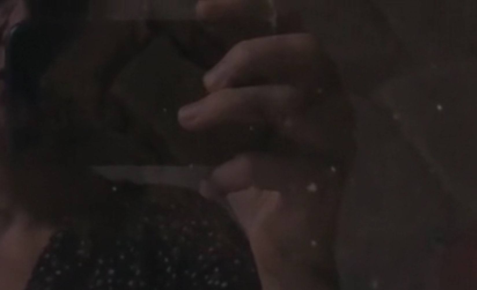 reflection in a computer screen of a hand filming the screen with mobile phone