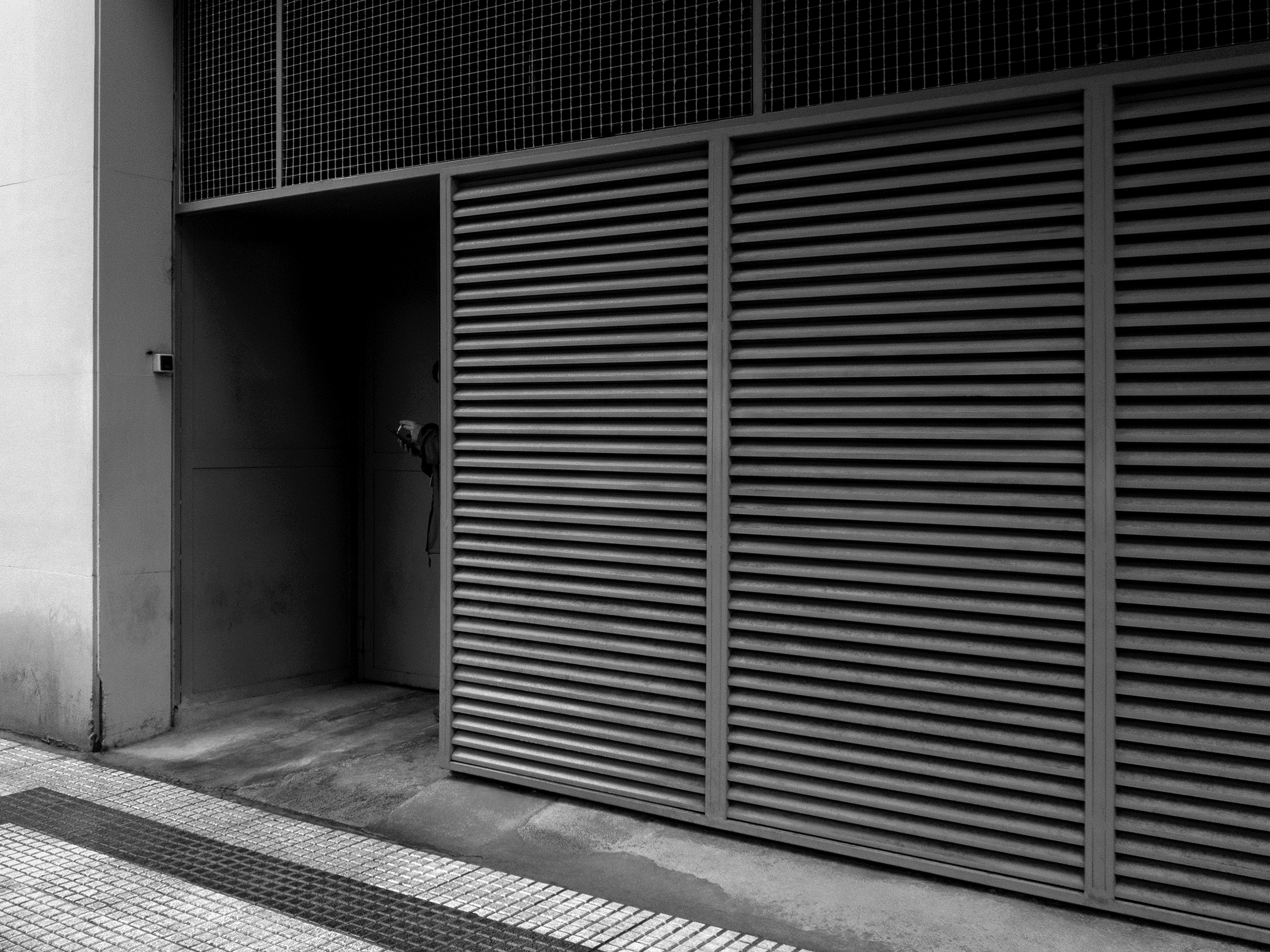 Woman smoking at the doors of her workplacePamplona, Spain, 2023photography, bw, single