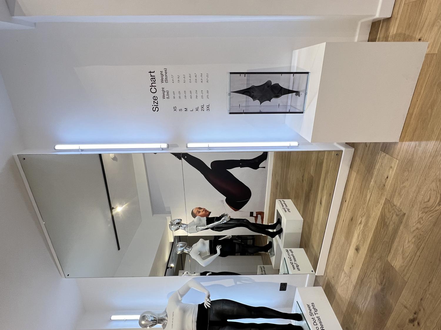 Interior of Sheertex pop-up store with mannequins in rip-resistant tights, size chart, and product display.