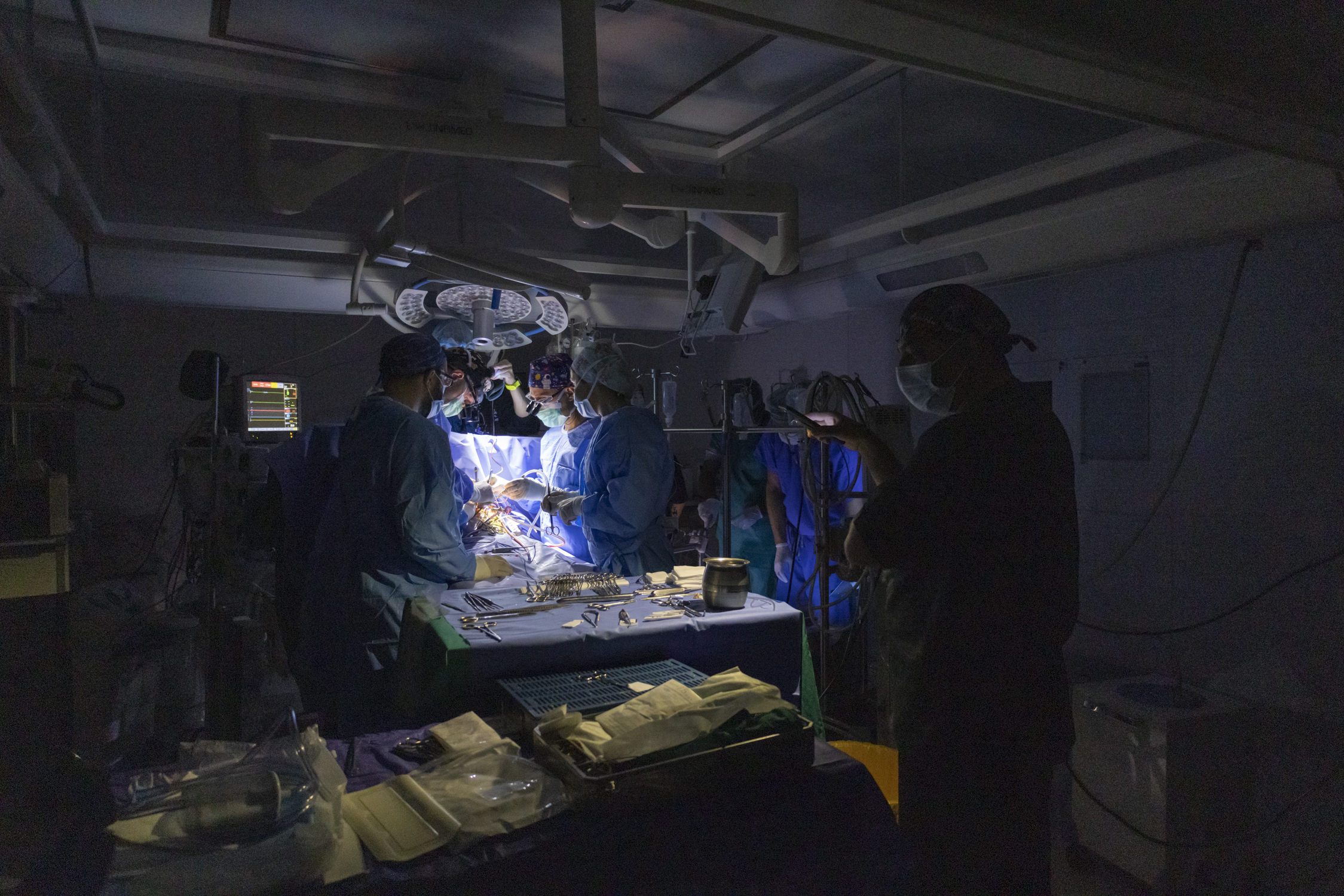 An Iraqi medical team holds their mobile phones above the surgical setting as the surgical team performs open heart surgery after an electrical power outage