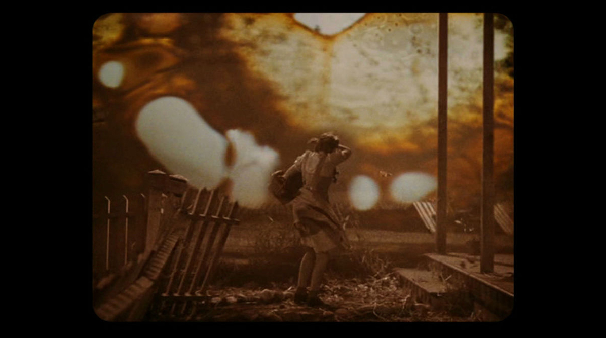 ID: Image from The Wizard of Oz movie. A sepia-toned Dorothy Gale is shielding her face from a storm. She has been superimposed against a background of a burned film reel.
