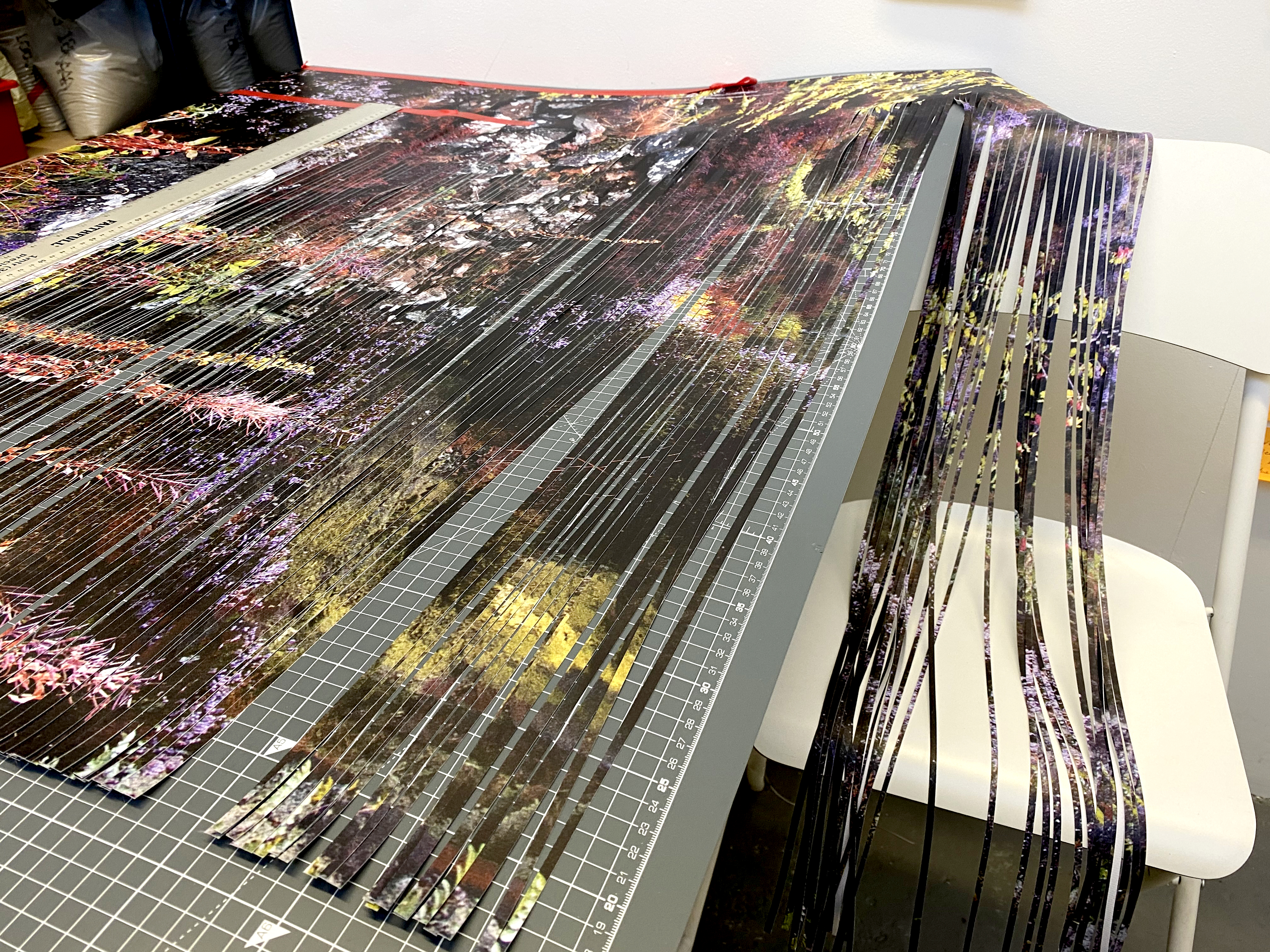Vinyl with a photographic print of a quarry being cut. The print spills over onto a chair showing the thin cut strands.