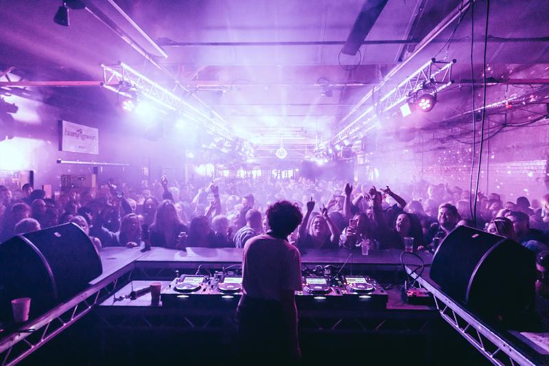 Annie Mac DJing to a full Belfast crowd bathed in pink light during the Before Midnight show at Banana Block.