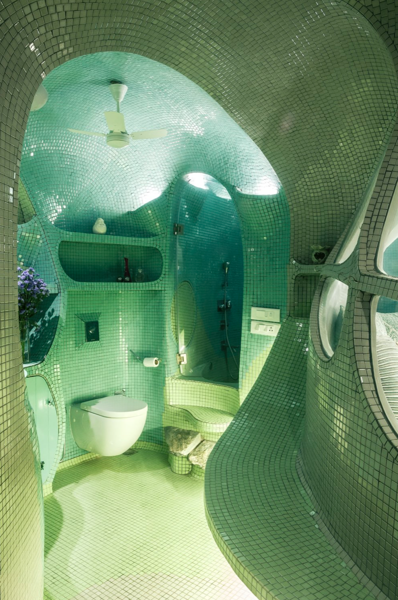 A Green bathroom covered with tile head to toe with organic curved walls.