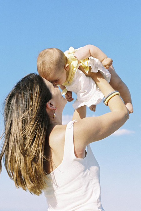 Mother holding baby in the sky of Fuerteventura, while photographer takes photos
