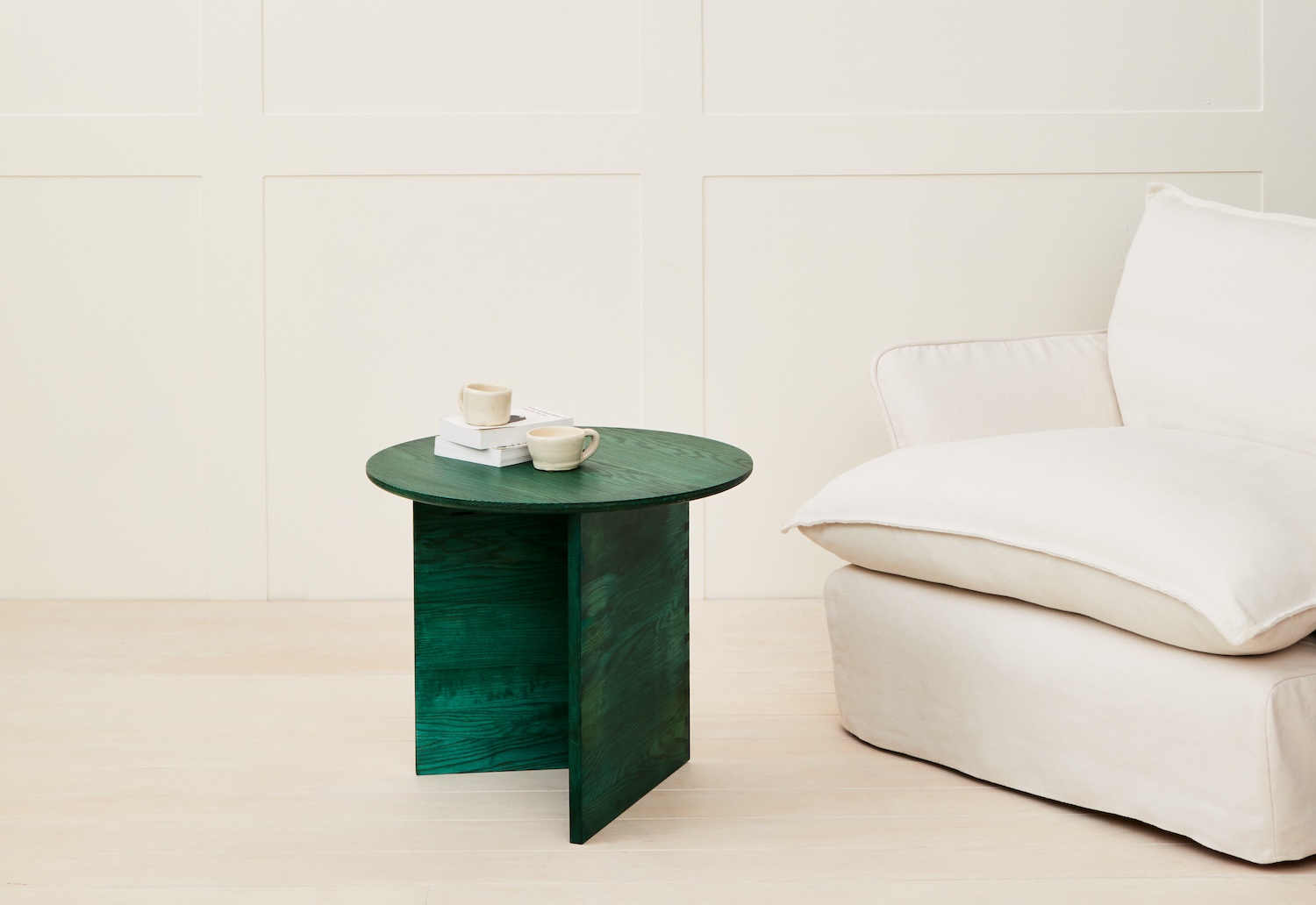 A round green side table next to a white armchair