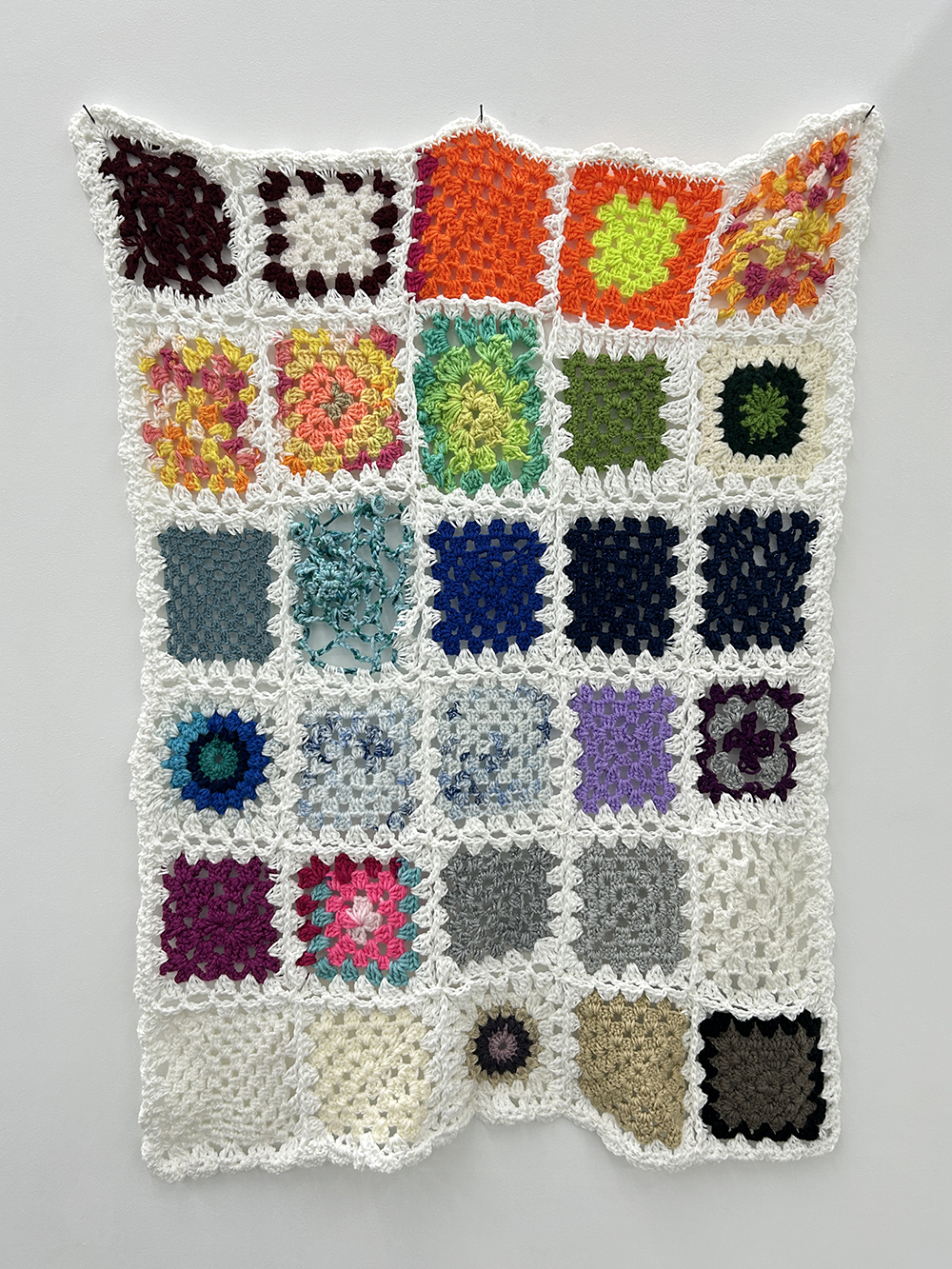 An artwork made of textile hangs on the wall.